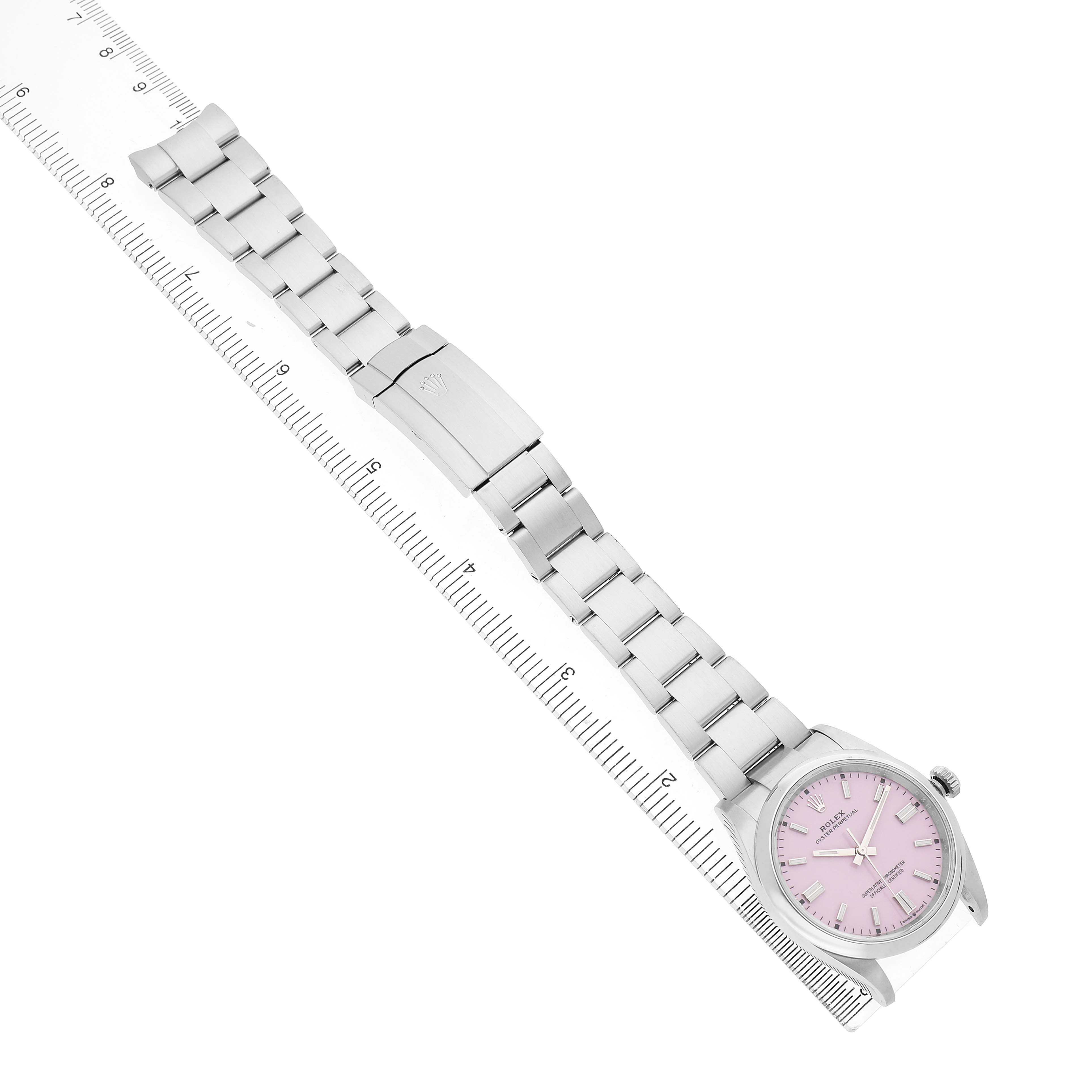 The Rolex Oyster Perpetual 126000 Men's Stainless Steel Pink Dial watch is shown at an angled top view with its full band and face visible alongside a ruler.