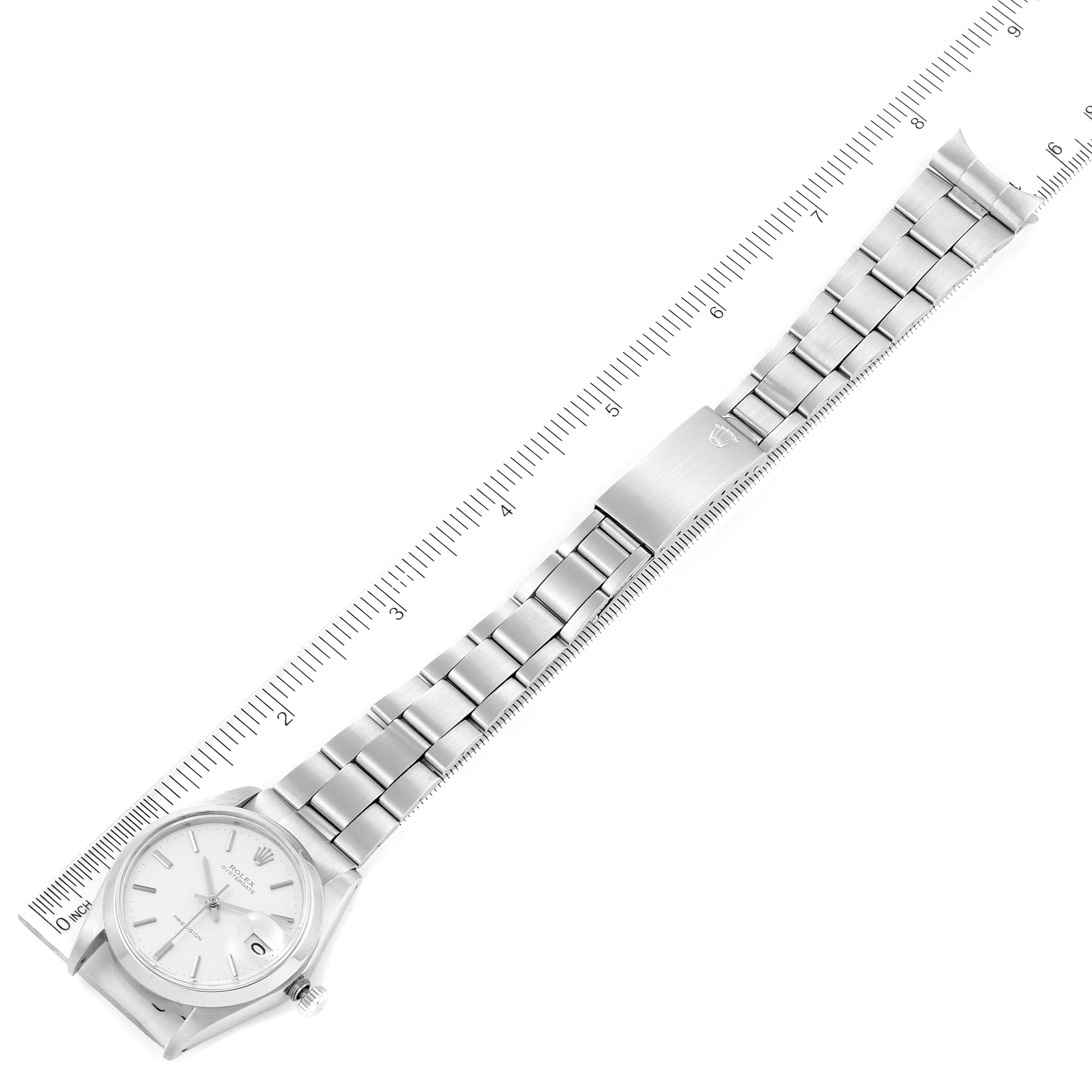 The image shows a Rolex Date 6694 Men's Stainless Steel Silver Dial 6694 Men's Stainless Steel Silver Dial model watch from a top-down angle, displaying the face, bracelet, and clasp against a ruler.