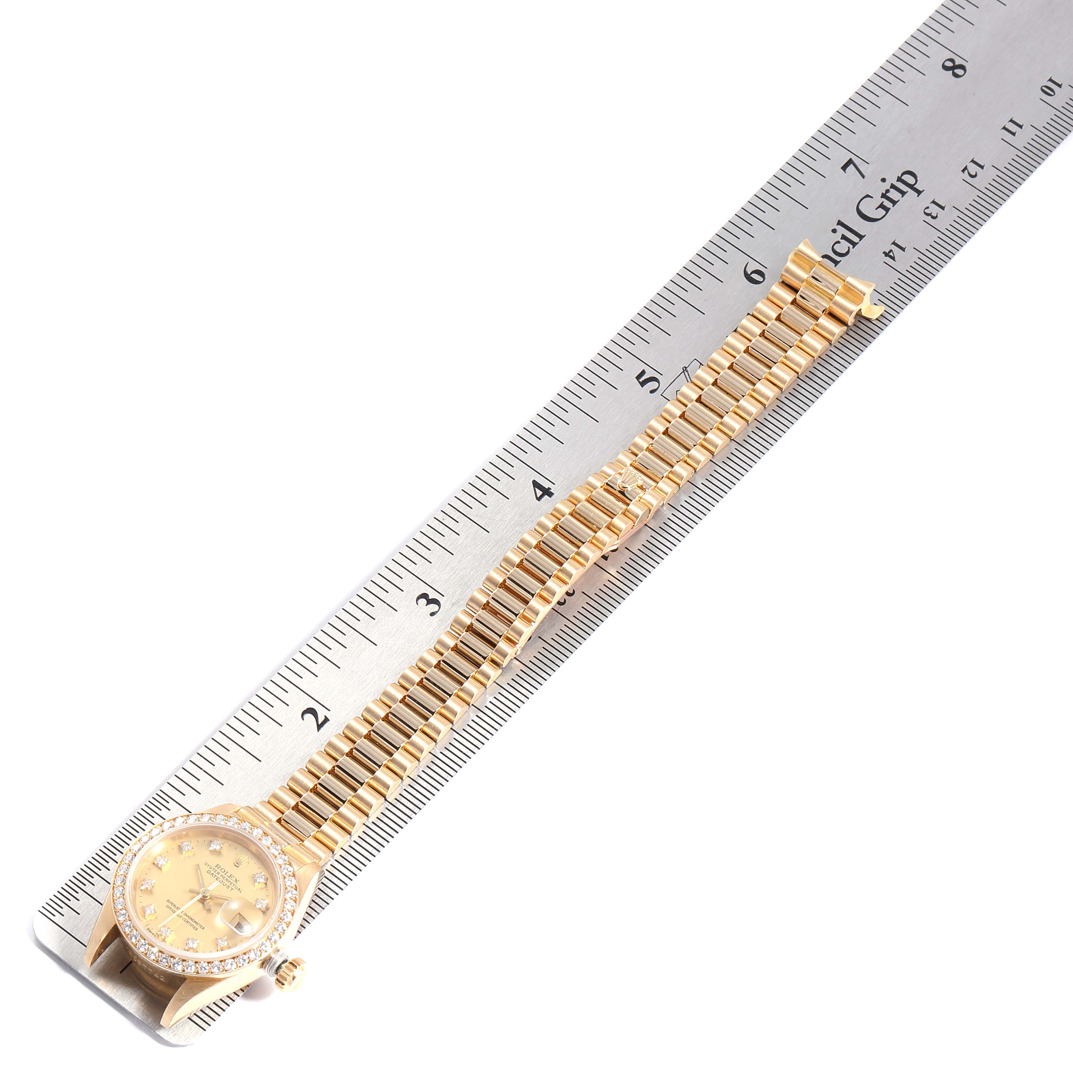 The image shows a Rolex President 69138 Women
s Yellow Gold Champagne Dial 69138 Women
s Yellow Gold Champagne Dial watch laid flat, with its bracelet extending alongside a ruler.