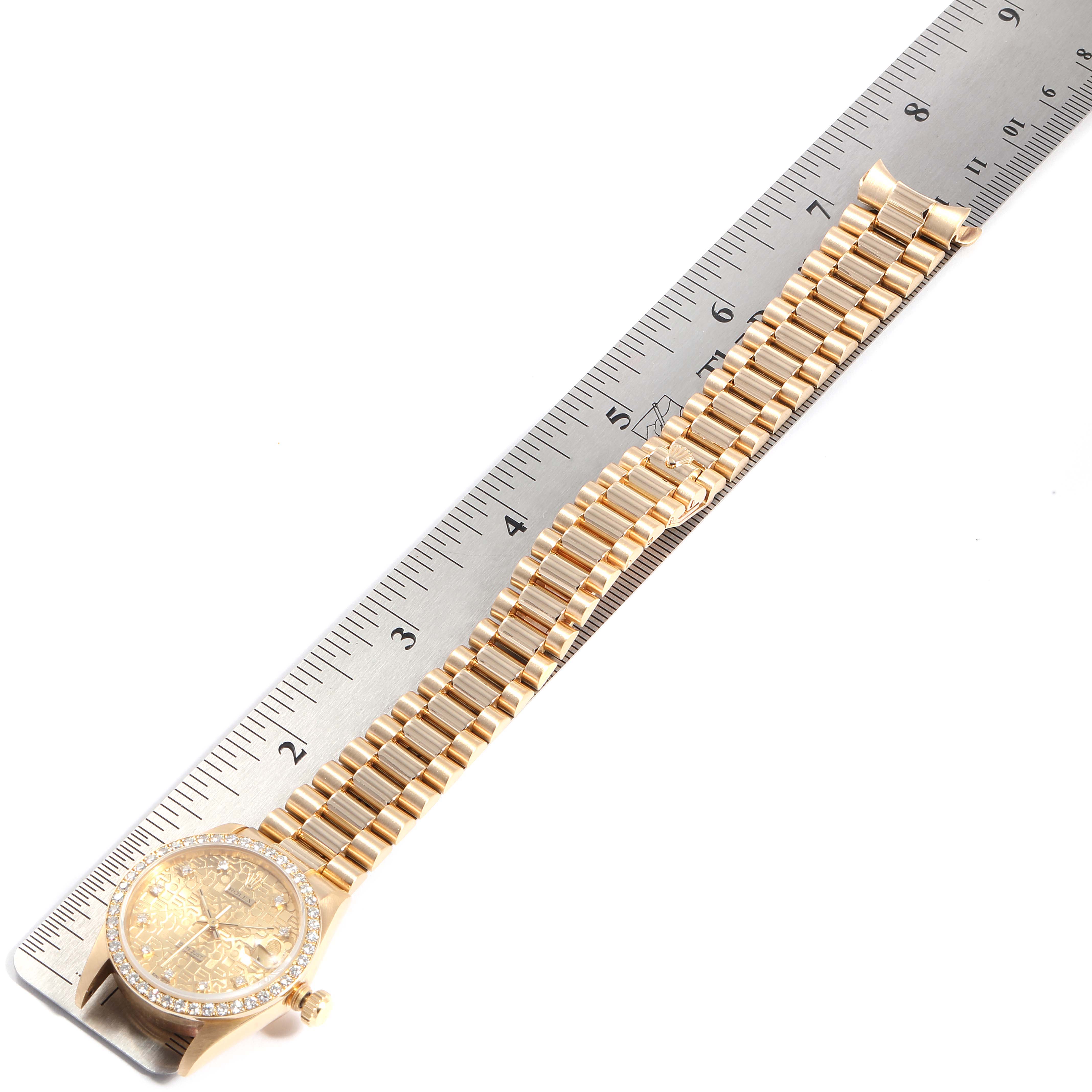 This image shows a Rolex President 68288 Women
s Yellow Gold Champagne Dial 68288 Women
s Yellow Gold Champagne Dial model watch from a top-down angle, alongside a measuring ruler showcasing its band and face.