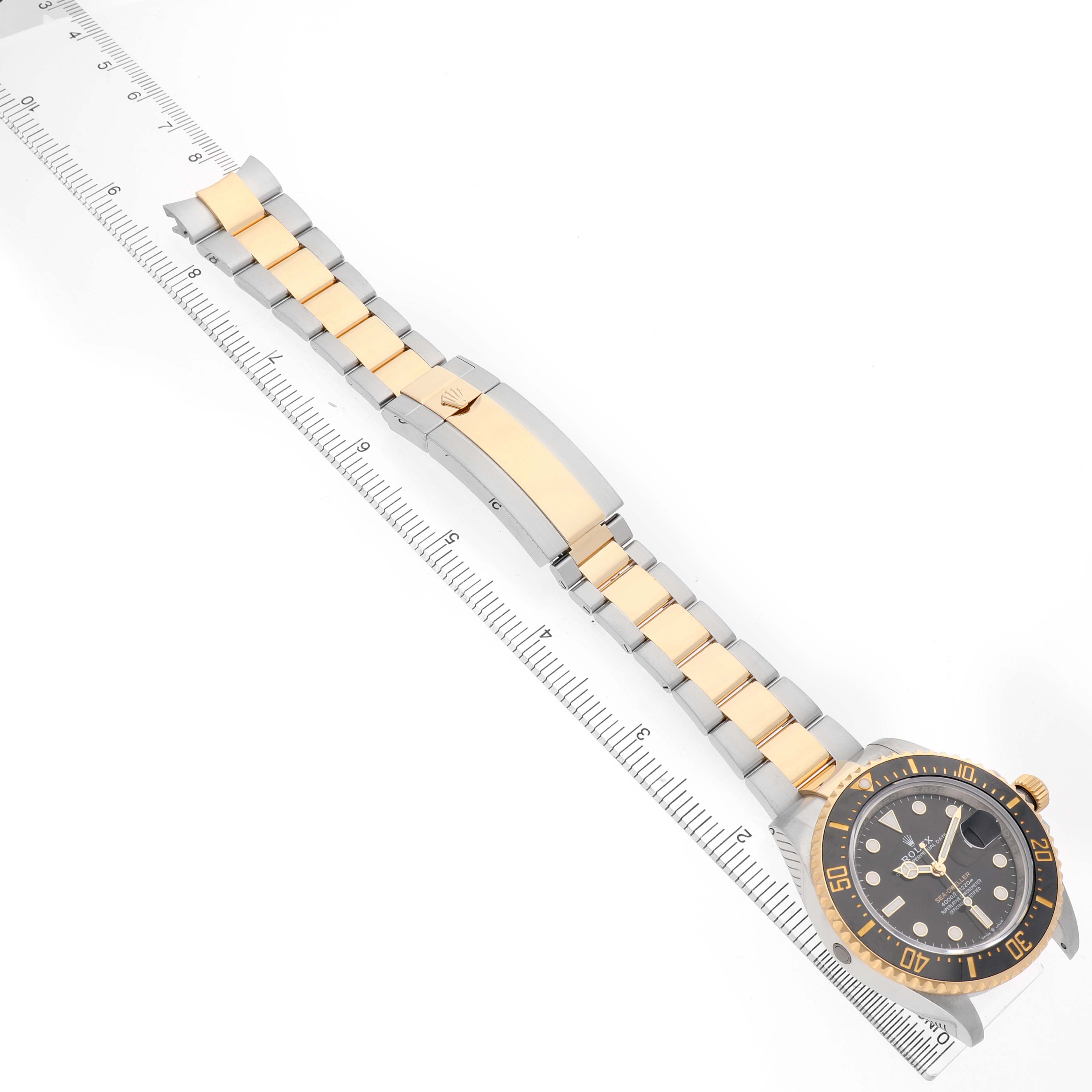 The Rolex Sea-Dweller 126603 Men's Steel and Gold (two tone) Black Dial watch is displayed from an angled overhead view, showing the dial, bezel, and two-tone bracelet alongside a ruler.