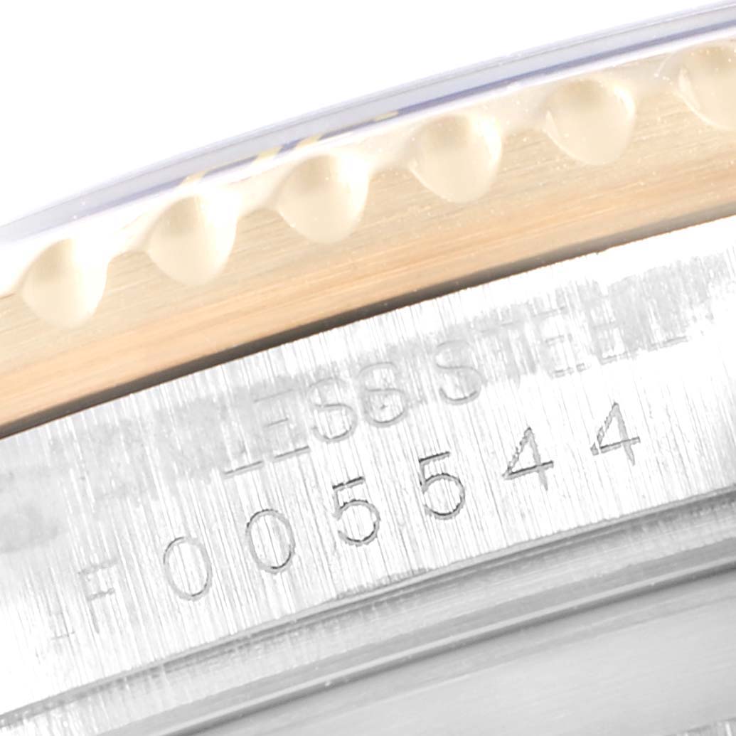 The image shows a close-up of the bezel and part of the case with engraved text on a Rolex Submariner 16613 Men
s Steel and Gold (two tone) Blue Dial 16613 Men
s Steel and Gold (two tone) Blue Dial watch.