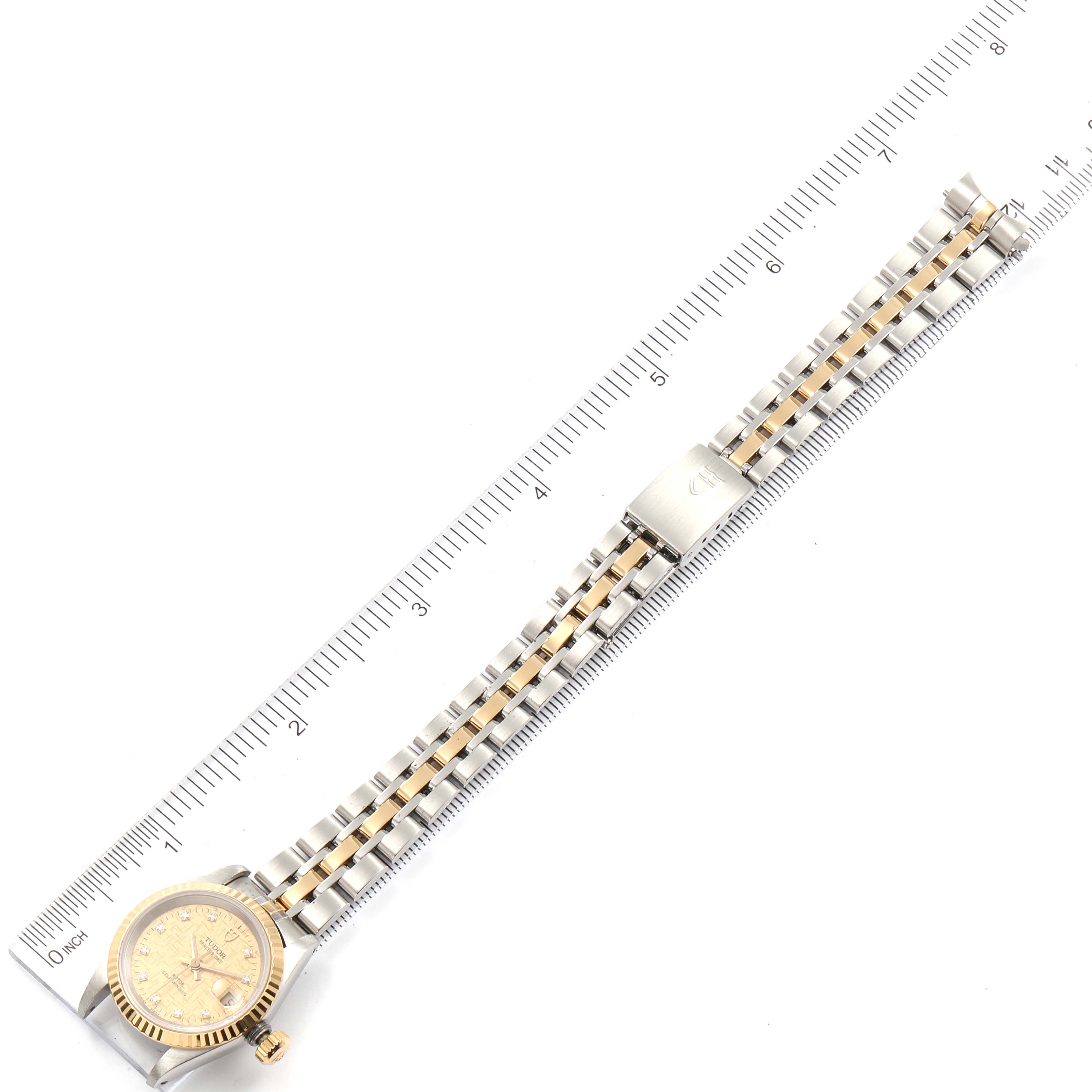 This image shows the Tudor Princess 92413 Women's Steel and Gold (two tone) Champagne Dial 92413 Women's Steel and Gold (two tone) Champagne Dial model watch laid flat with its band stretched out beside a ruler.