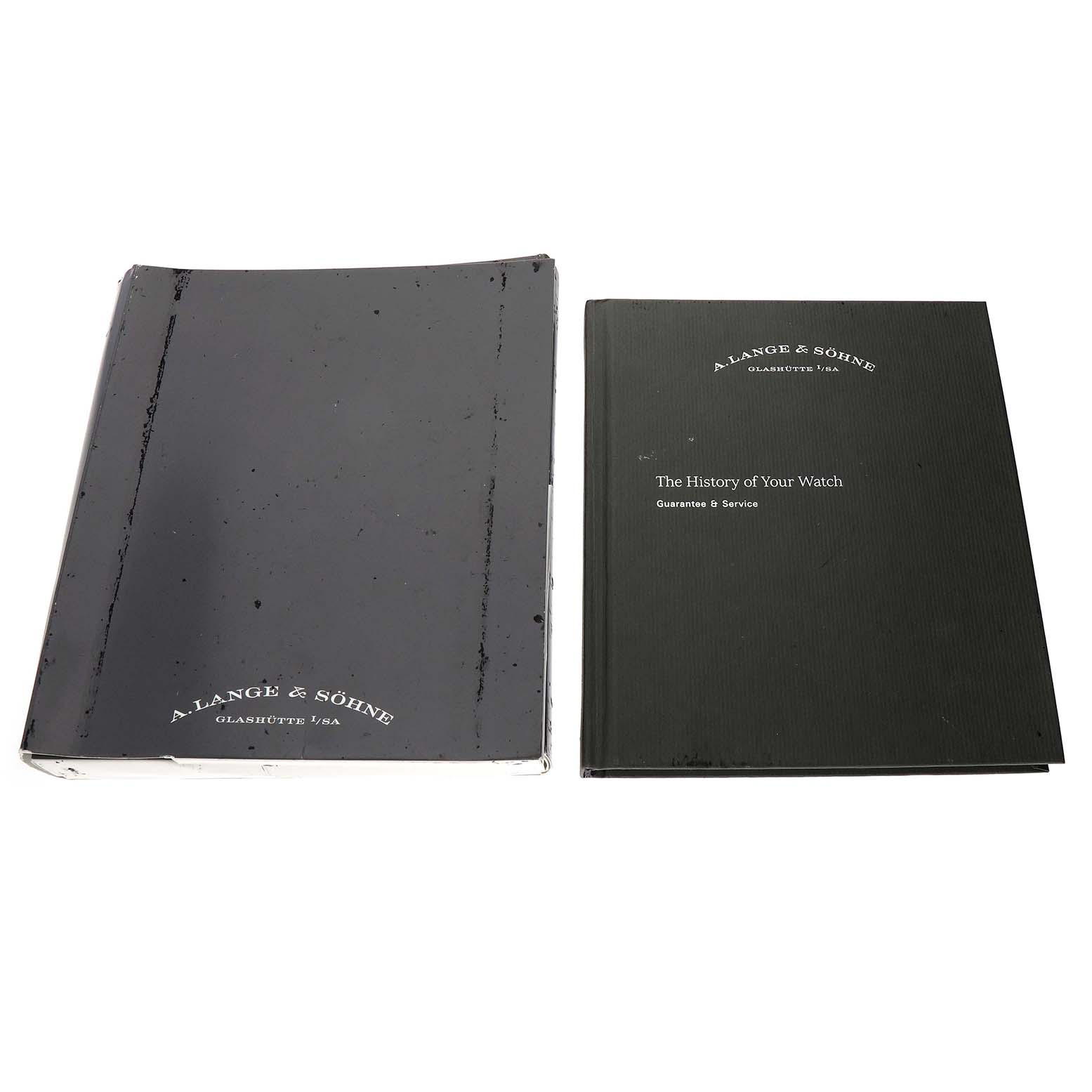 The image shows two books related to the Saxonia model by A. Lange & Söhne, likely for history and guarantee/service details.