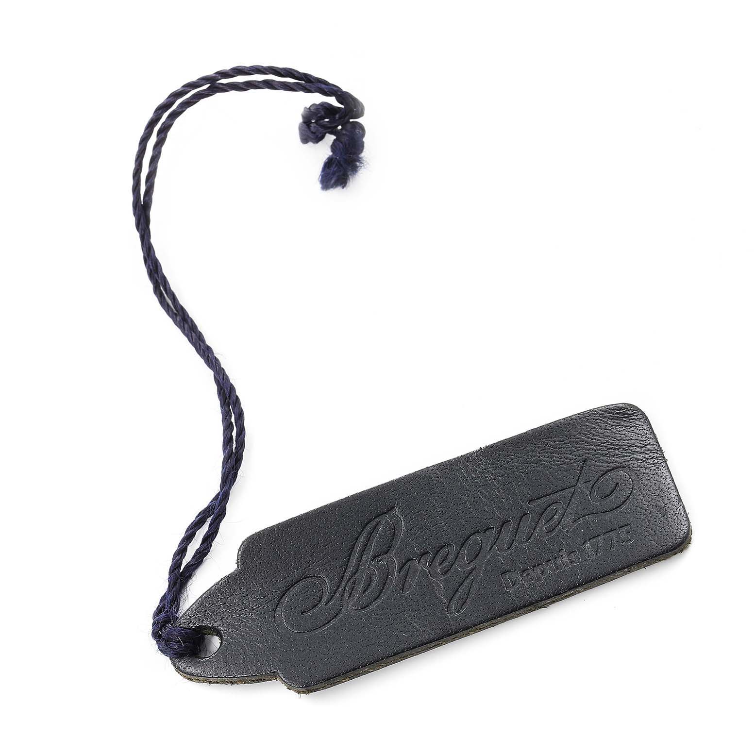 This image shows a Breguet Classique 5177BA/12/9V6 Men's Yellow Gold Silver Dial 5177BA/12/9V6 Men's Yellow Gold Silver Dial watch accessory tag with embossed branding and a braided string attachment.