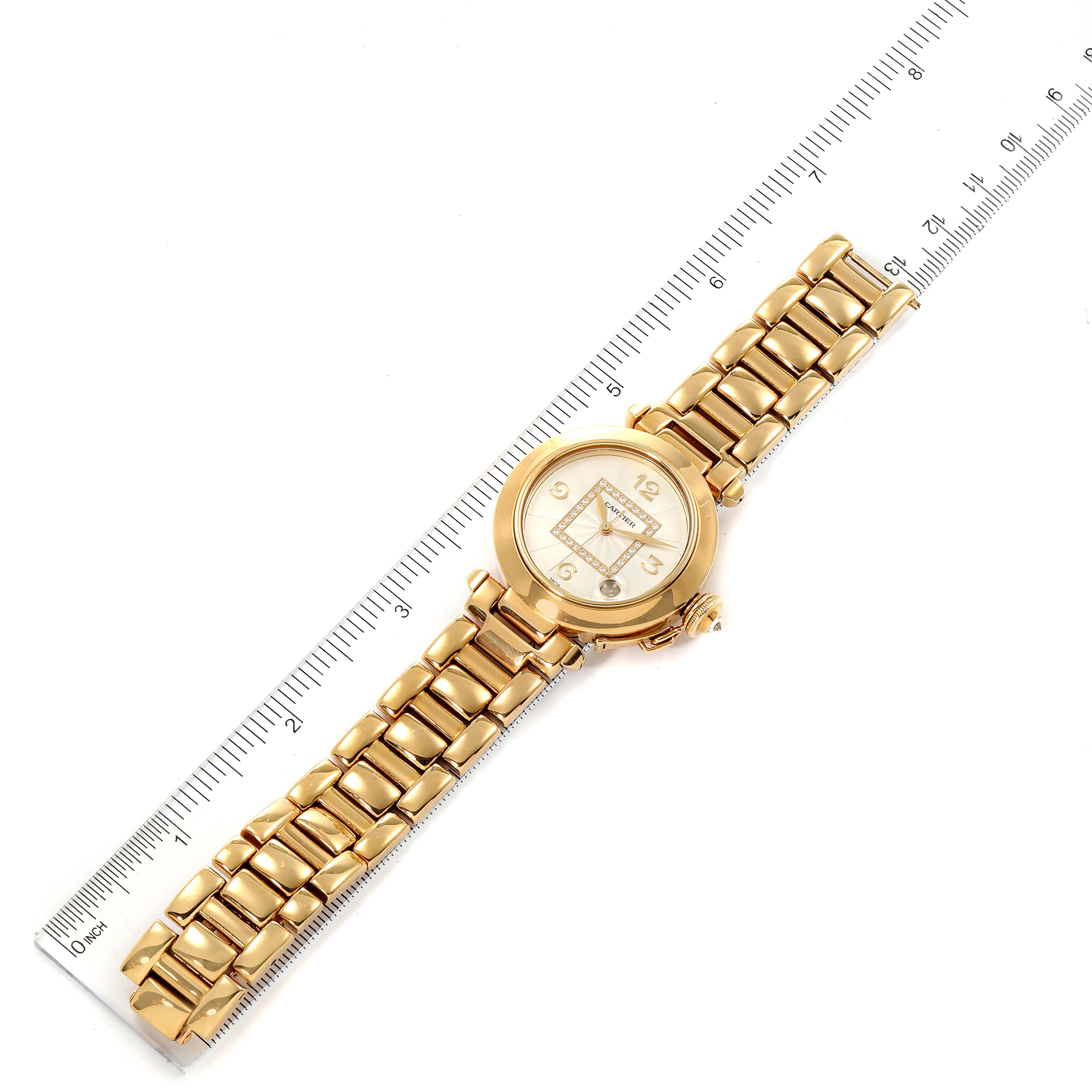 The Cartier Pasha WJ1110H9 Women's Yellow Gold Silver Dial WJ1110H9 Women's Yellow Gold Silver Dial watch is shown from a top-down angle, displaying the face, bezel, and bracelet against a ruler for size reference.