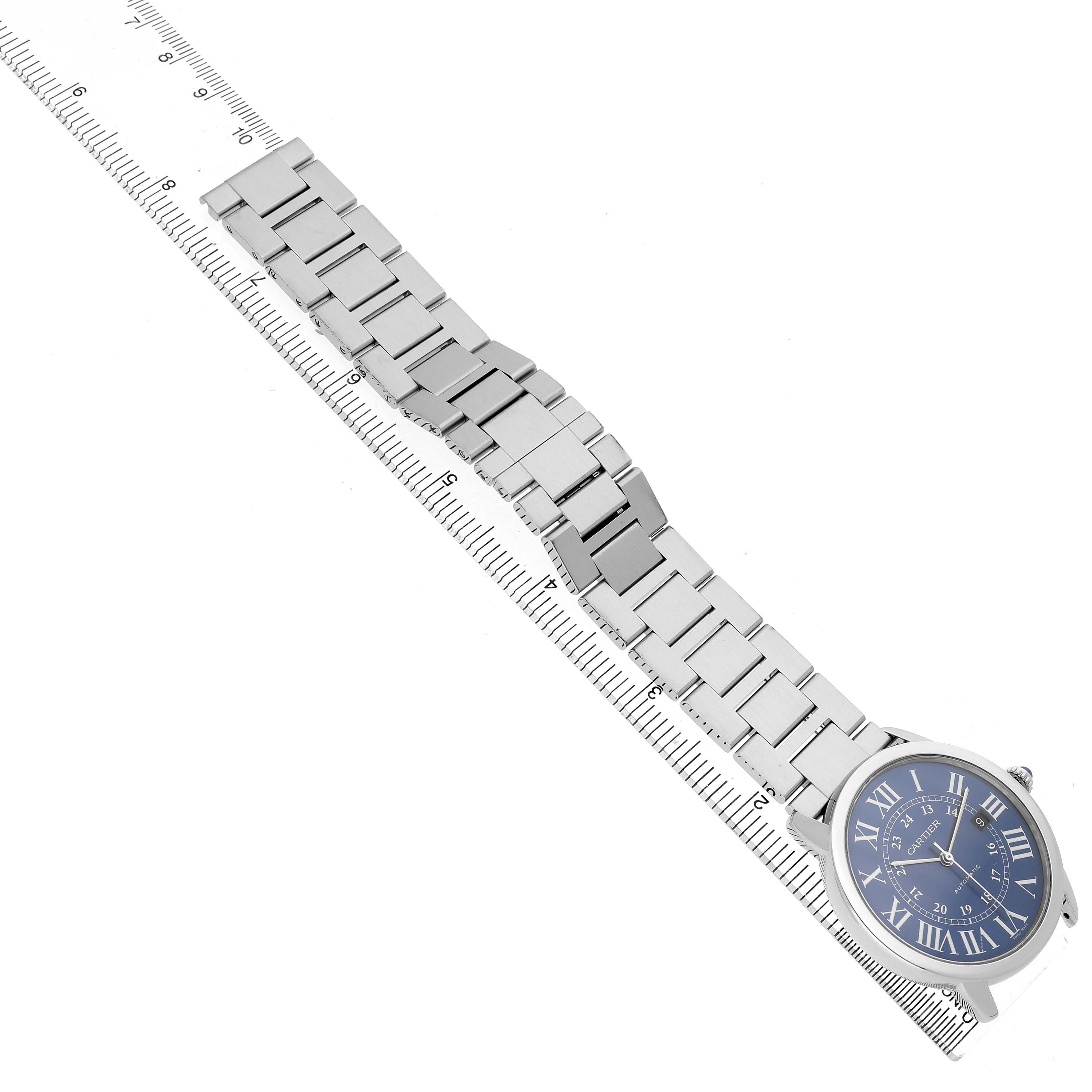 The Cartier Ronde WSRN0023 Men's Stainless Steel Blue Dial watch is shown at an angled top view, highlighting its blue dial, metal bracelet, and ruler for scale.