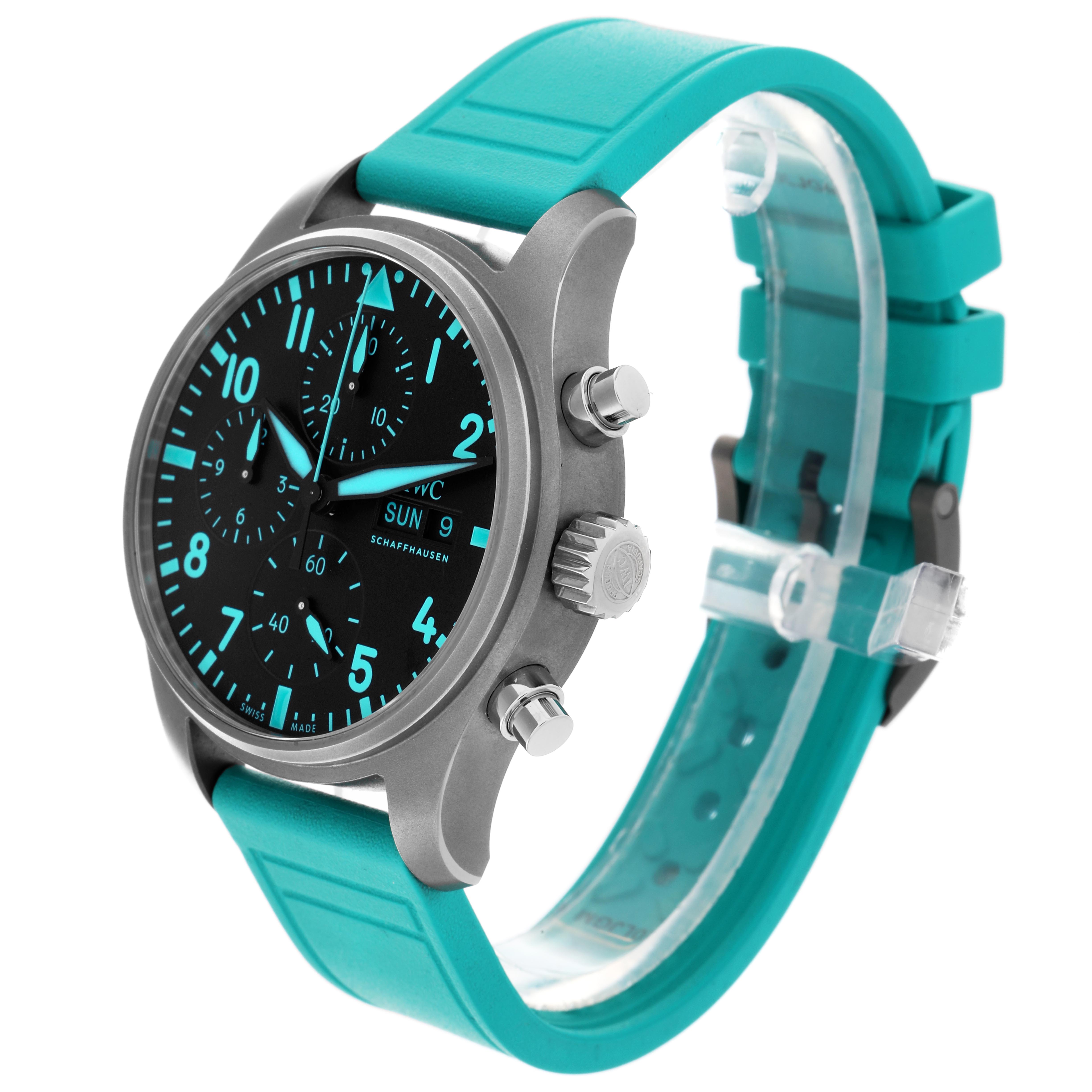 The IWC Pilot IW388108 Men's Titanium Black Dial model watch is shown at a slight angle, highlighting the face, crown, pushers, and the turquoise strap.