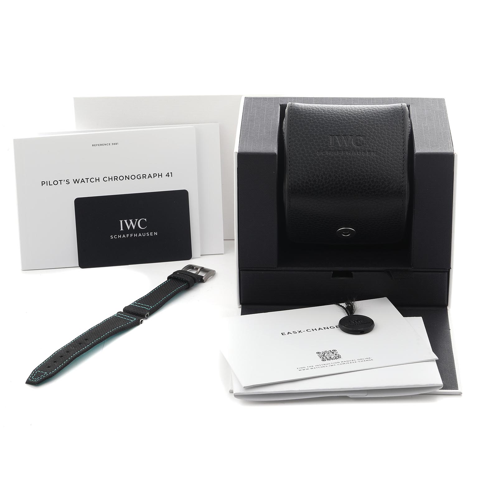 The image shows an angled view of the IWC Pilot IW388108 Men's Titanium Black Dial's Watch box, strap, and accompanying documents.