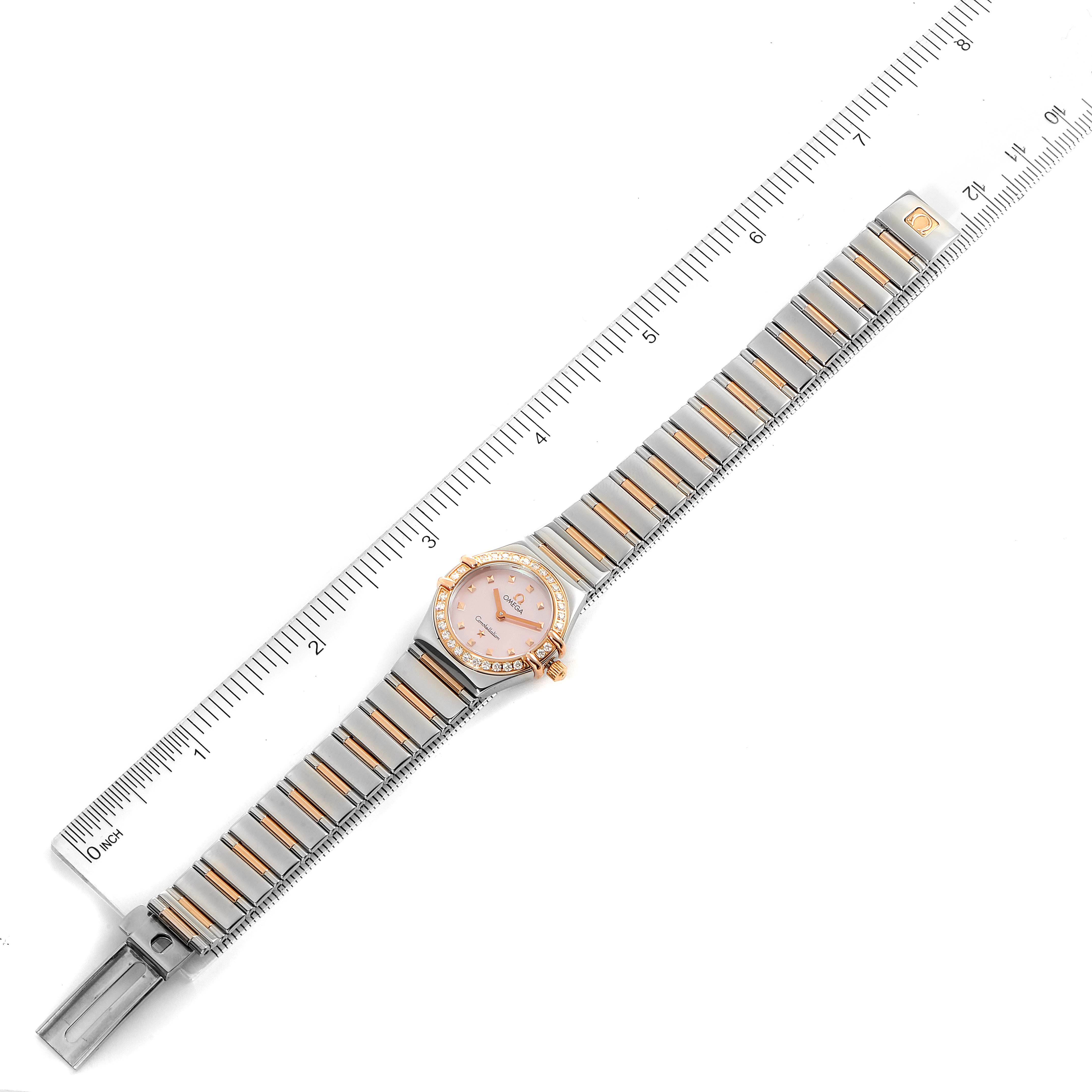 The image shows the Omega 1365.71.00 Women
s Steel and Gold (two tone) Mother of Pearl Dial 1365.71.00 Women
s Steel and Gold (two tone) Mother of Pearl Dial Constellation Steel Rose Gold Diamond Mini Ladies Watch 1365.71.00 laid flat next to a ruler.