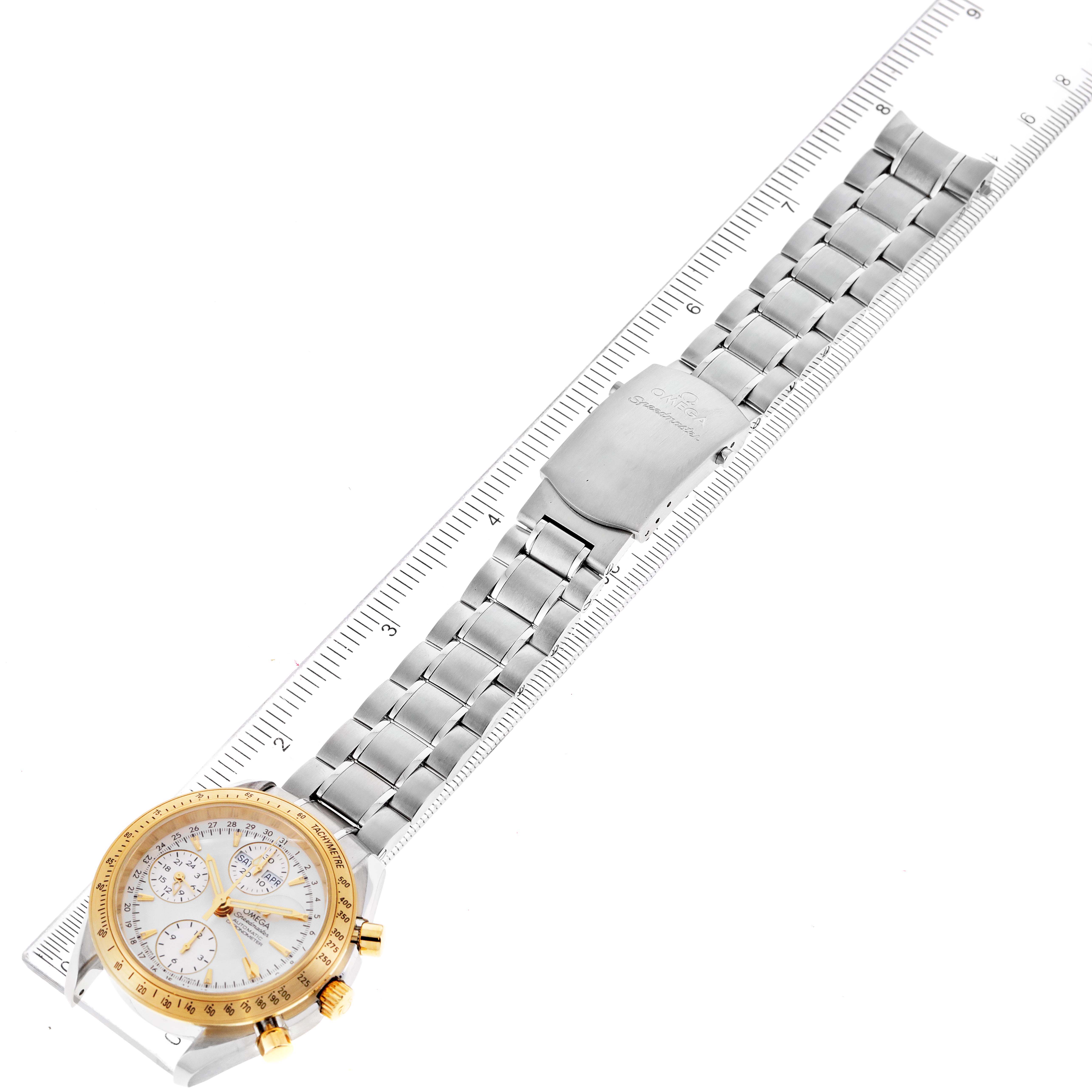 The Omega Speedmaster 323.21.40.44.02.001 Men's Steel and Gold (two tone) Silver Dial 323.21.40.44.02.001 Men's Steel and Gold (two tone) Silver Dial watch is shown from an angled top view, displaying the full metal band and face alongside a ruler for scale.