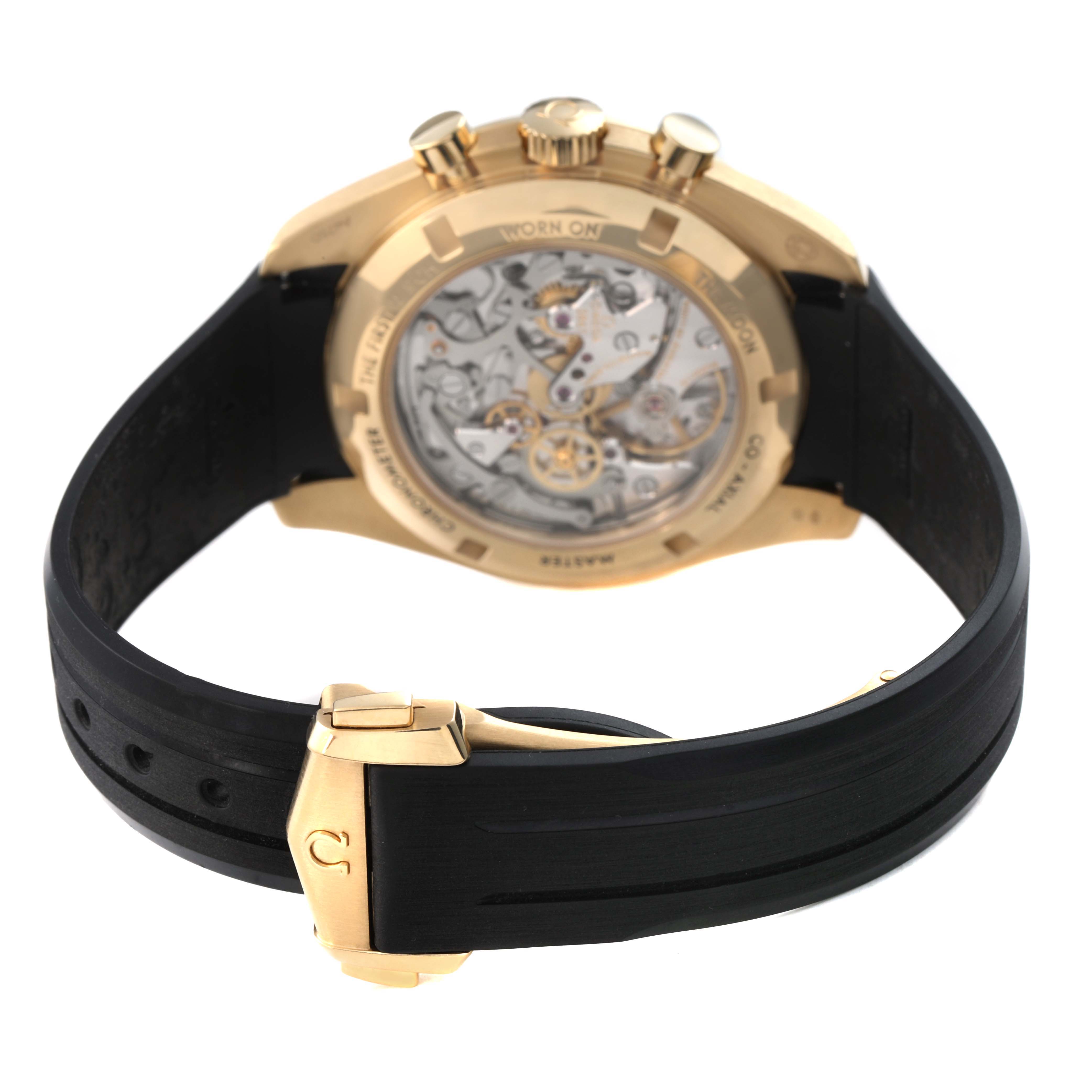The Omega Speedmaster 310.62.42.50.99.001 Men's Yellow Gold Black Dial watch is shown from the back, highlighting the transparent case back and movement, with a black strap.