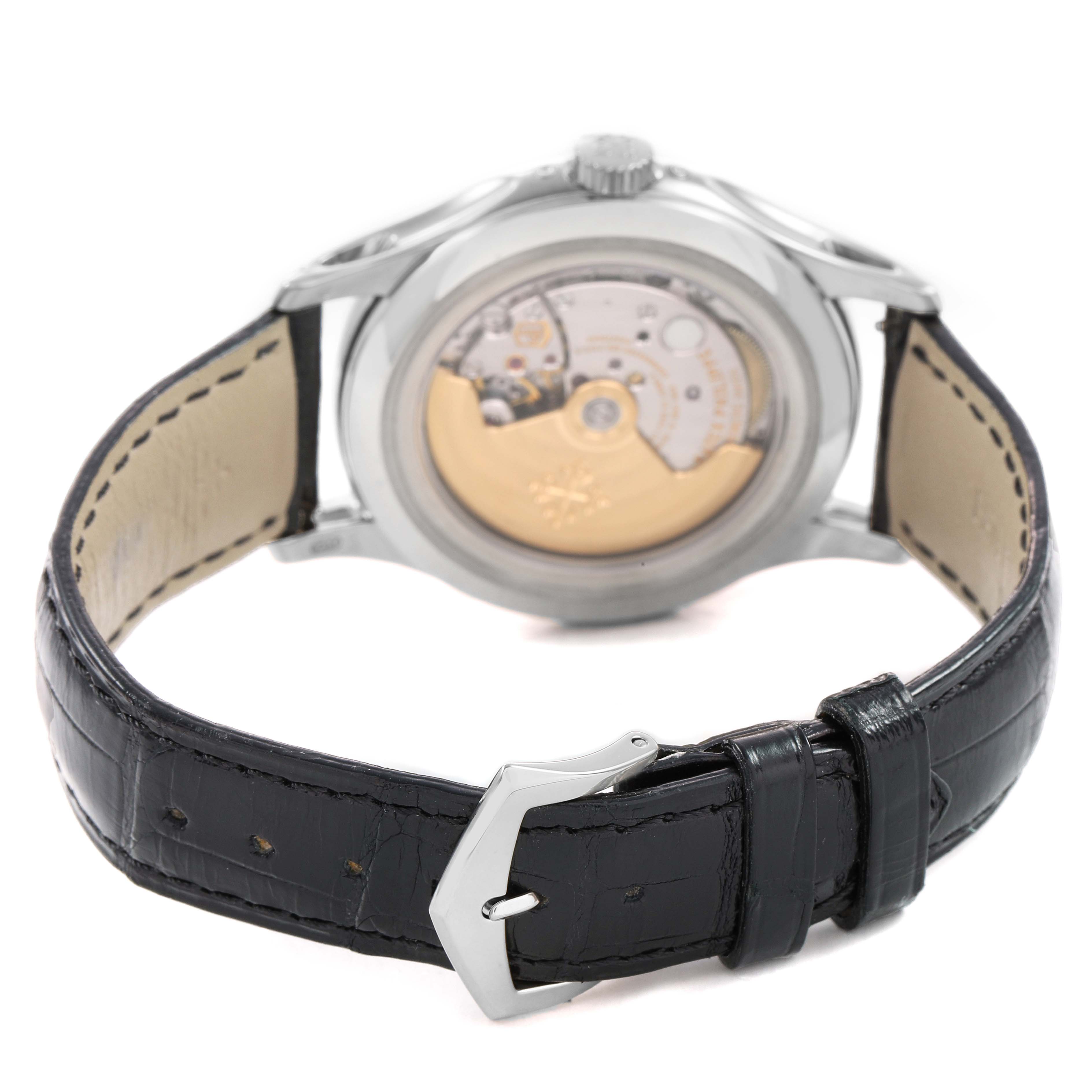 The Patek Philippe Complications 5205G Men's White Gold Silver Dial watch is shown from the back, highlighting its open case back and black leather strap.