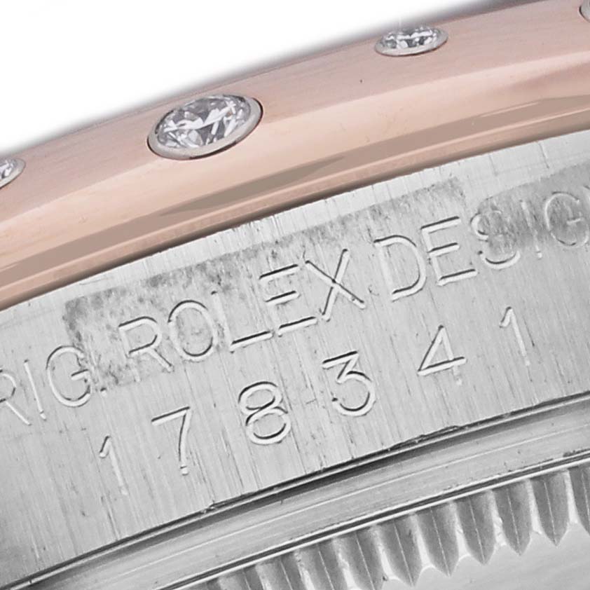 This close-up image of the Rolex Mid-Size 178341 Women's Steel and Gold (two tone) Mother of Pearl Dial 178341 Women's Steel and Gold (two tone) Mother of Pearl Dial watch shows the engraved serial number and a portion of the diamond-studded bezel.