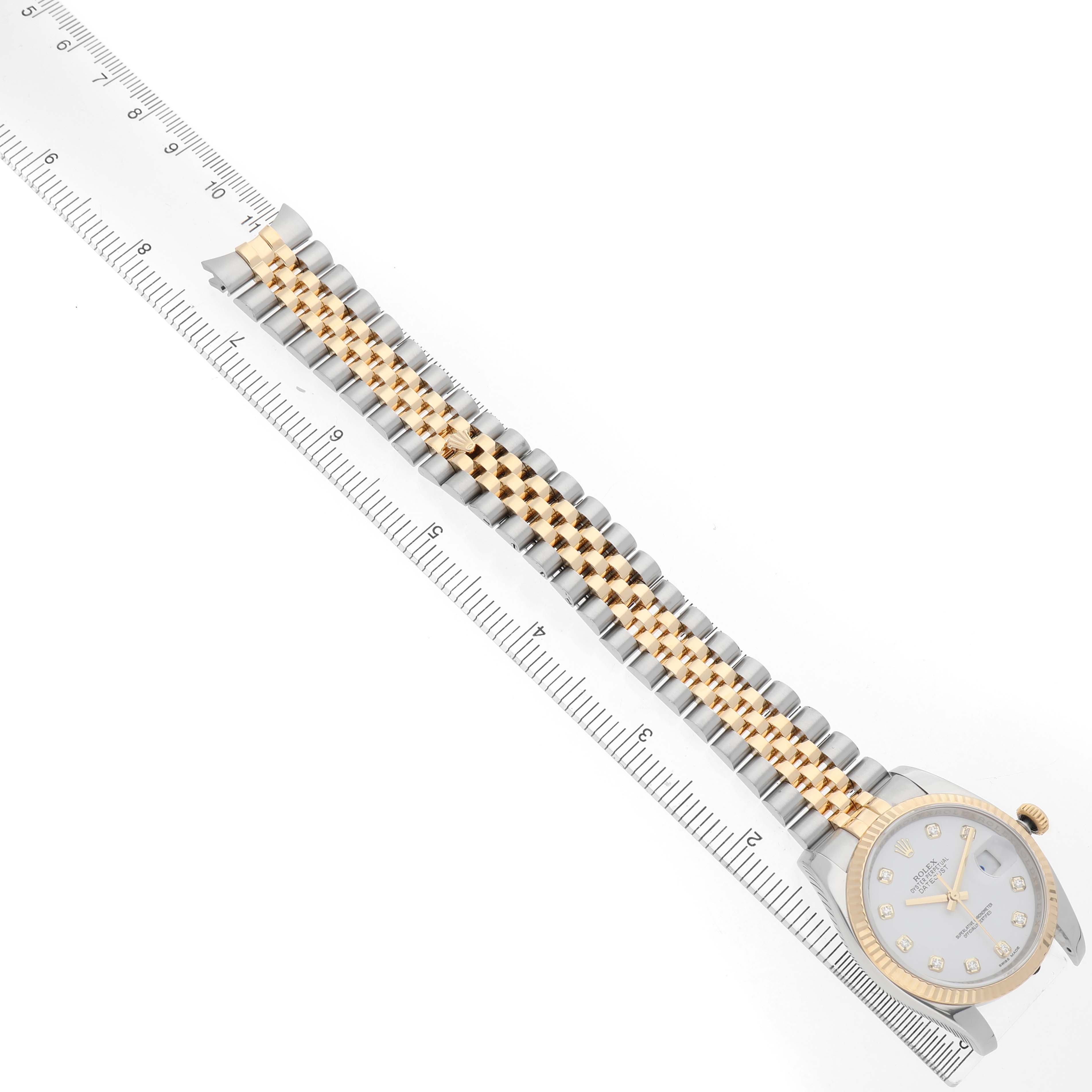 The Rolex Datejust 116233 Men's Steel and Gold (two tone) White Dial watch is shown at an angle displaying the full bracelet and dial with a ruler parallel to it.