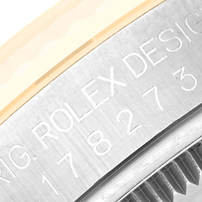 This close-up angle of the Rolex Mid-Size 178273 Women's Steel and Gold (two tone) Black Dial 178273 Women's Steel and Gold (two tone) Black Dial watch shows part of the bezel and caseback with engraved text.