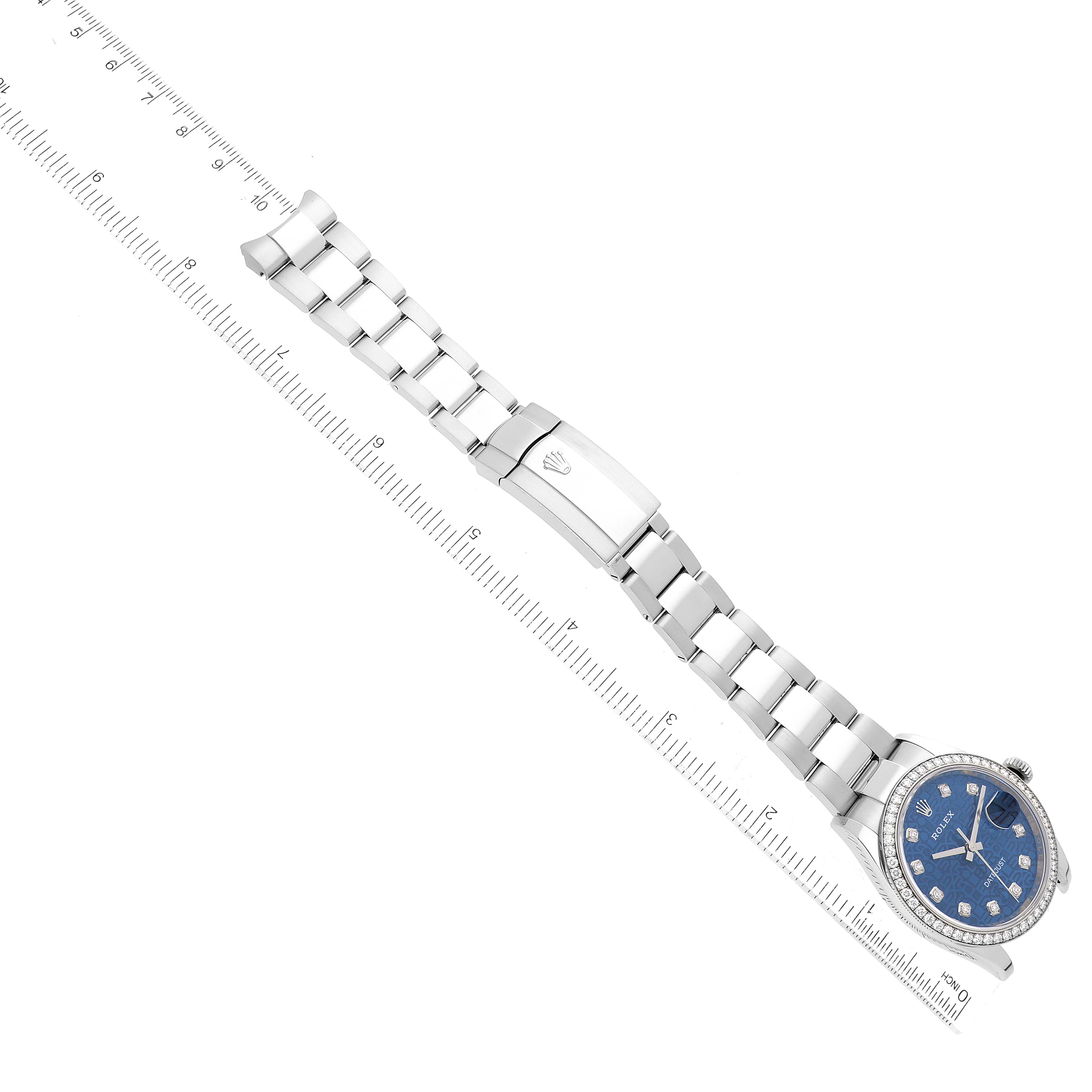The image shows a Rolex Datejust 126284RBR Men's Stainless Steel Blue Dial 126284RBR Men's Stainless Steel Blue Dial watch laid flat alongside a ruler, displaying the bracelet and watch face at an angled top view.