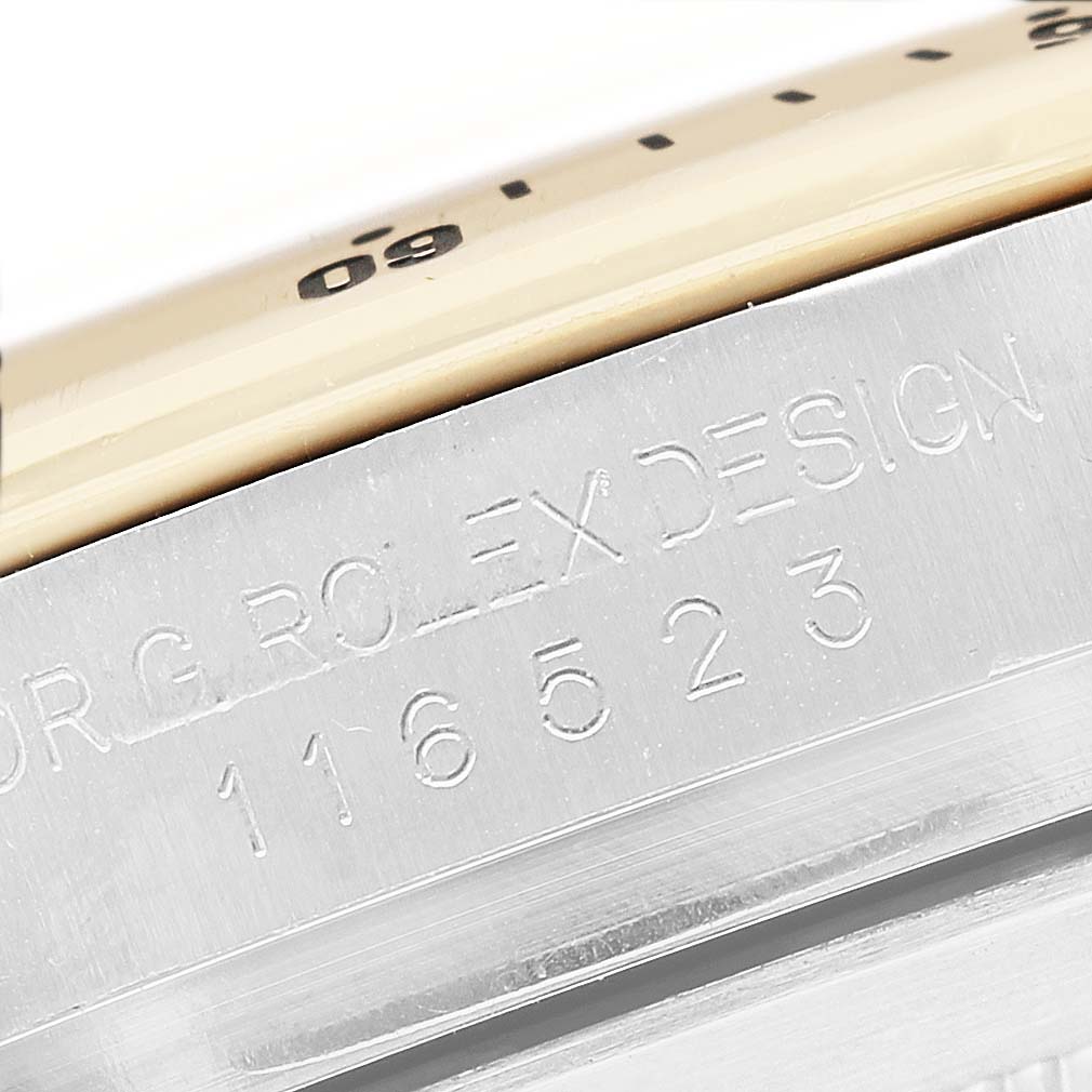 The image shows a close-up of the engraved edge detailing and partial bezel of a Rolex Daytona 116523 Men's Steel and Gold (two tone) Silver Dial watch.