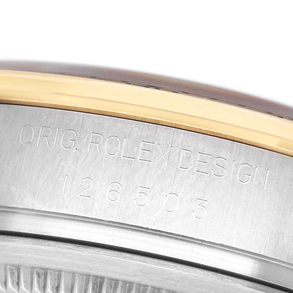 The image shows a close-up of the engraved bezel edge of a Rolex Daytona M126503-0001 Men's Steel and Gold (two tone) White Dial, highlighting the "ORIG. ROLEX DESIGN" text and model number.