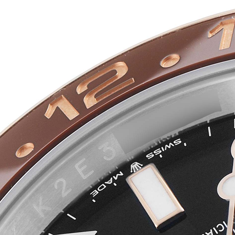 This close-up image of a Rolex GMT-Master 126711CHNR Men's Steel and Gold (two tone) Black Dial 126711CHNR Men's Steel and Gold (two tone) Black Dial watch shows the bezel, part of the dial, and hour marker.