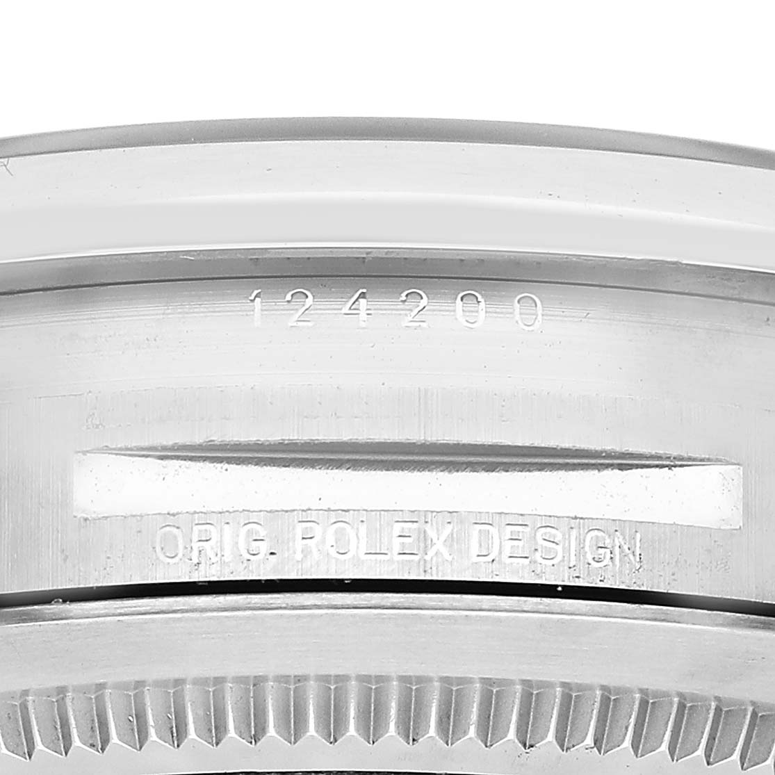 The image shows a close-up of the case side of a Rolex Oyster Perpetual 124200 Men's Stainless Steel Pink Dial, focusing on the serial number and design engraving.