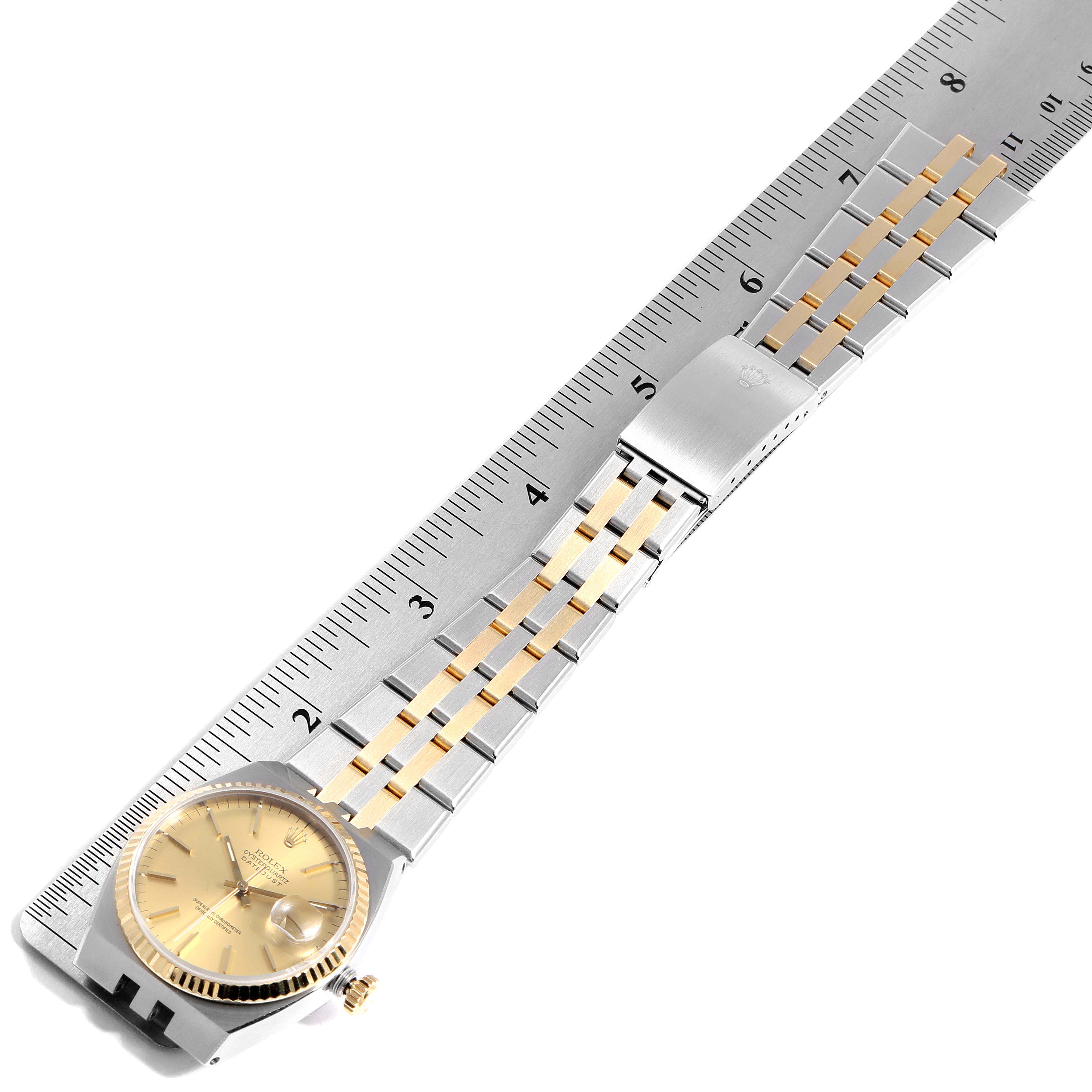 The image shows a Rolex Oysterquartz 17013 Men
s Steel and Gold (two tone) Champagne Dial 17013 Men
s Steel and Gold (two tone) Champagne Dial watch laid flat next to a ruler, highlighting the face, band, and clasp.