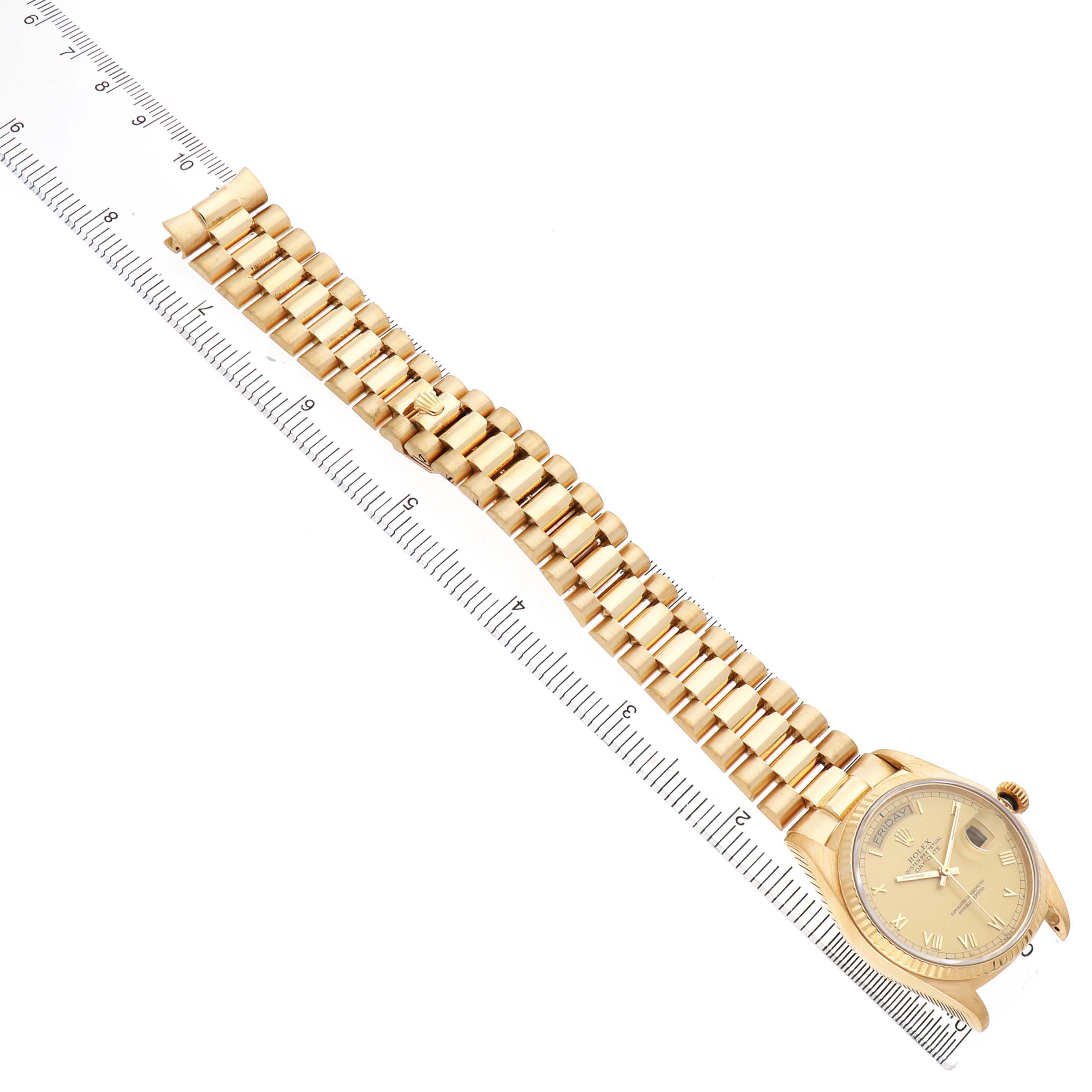 The Rolex President 18038 Men's Yellow Gold Champagne Dial watch is shown from a top-down angle displaying the full band and watch face alongside a ruler for scale.
