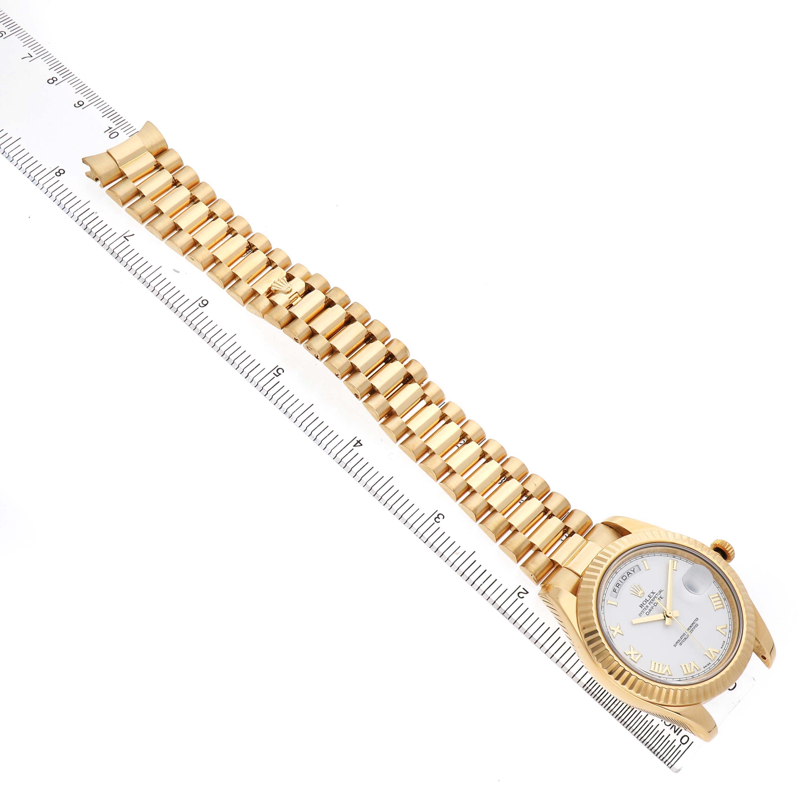 The Rolex President 218238 Men's Yellow Gold White Dial watch is shown at a diagonal angle, displaying the dial and full bracelet alongside a ruler for size reference.