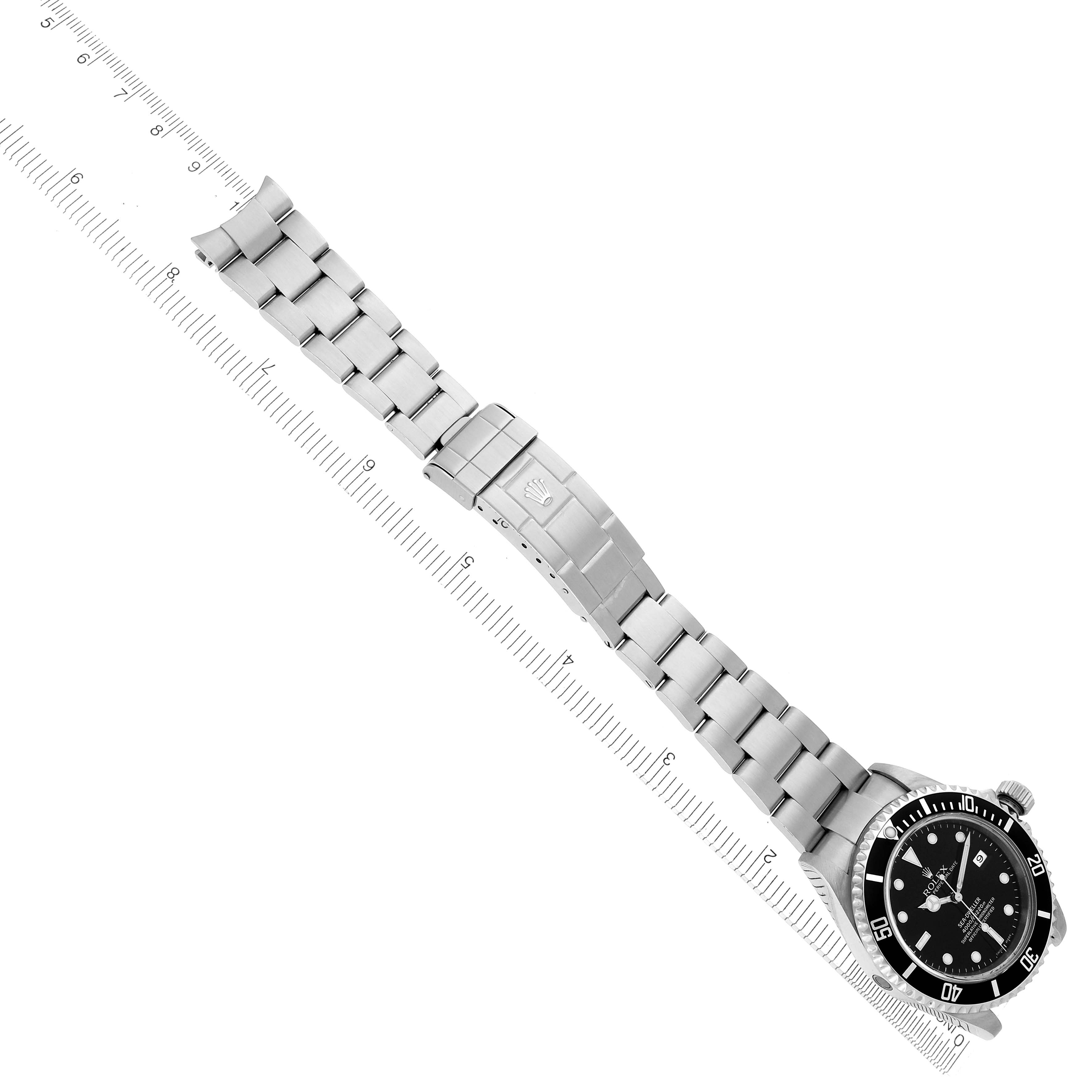 The Rolex Sea-Dweller 16600 Men's Stainless Steel Black Dial watch is shown at a top-down angle, highlighting the face, bracelet, and clasp next to a ruler for size reference.