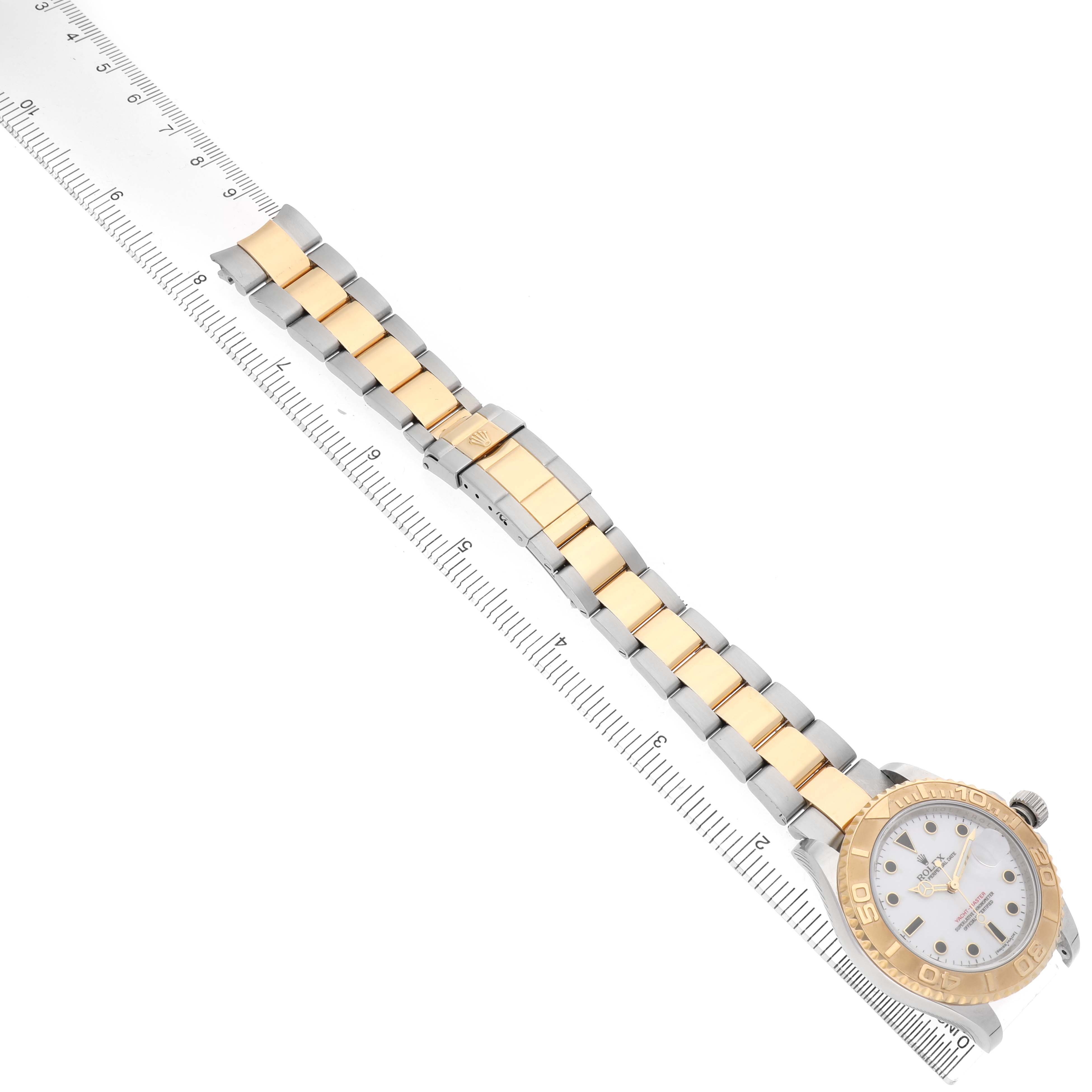 The Rolex Yacht-Master 16623 Men's Steel and Gold (two tone) White Dial watch is shown from an angled top view, displaying the bracelet and case alongside a ruler.