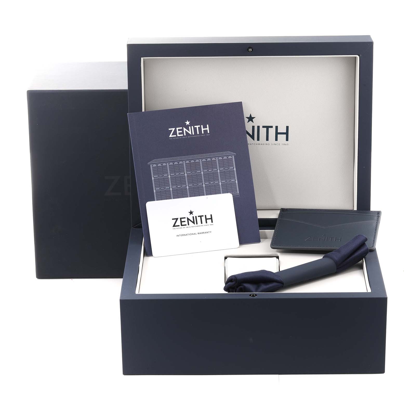 The image shows a Zenith Chronomaster 03.3101.3600 Men's Stainless Steel Black Dial 03.3101.3600 Men's Stainless Steel Black Dial watch box, warranty card, booklet, leather card holder, and cleaning cloth at a frontal angle.