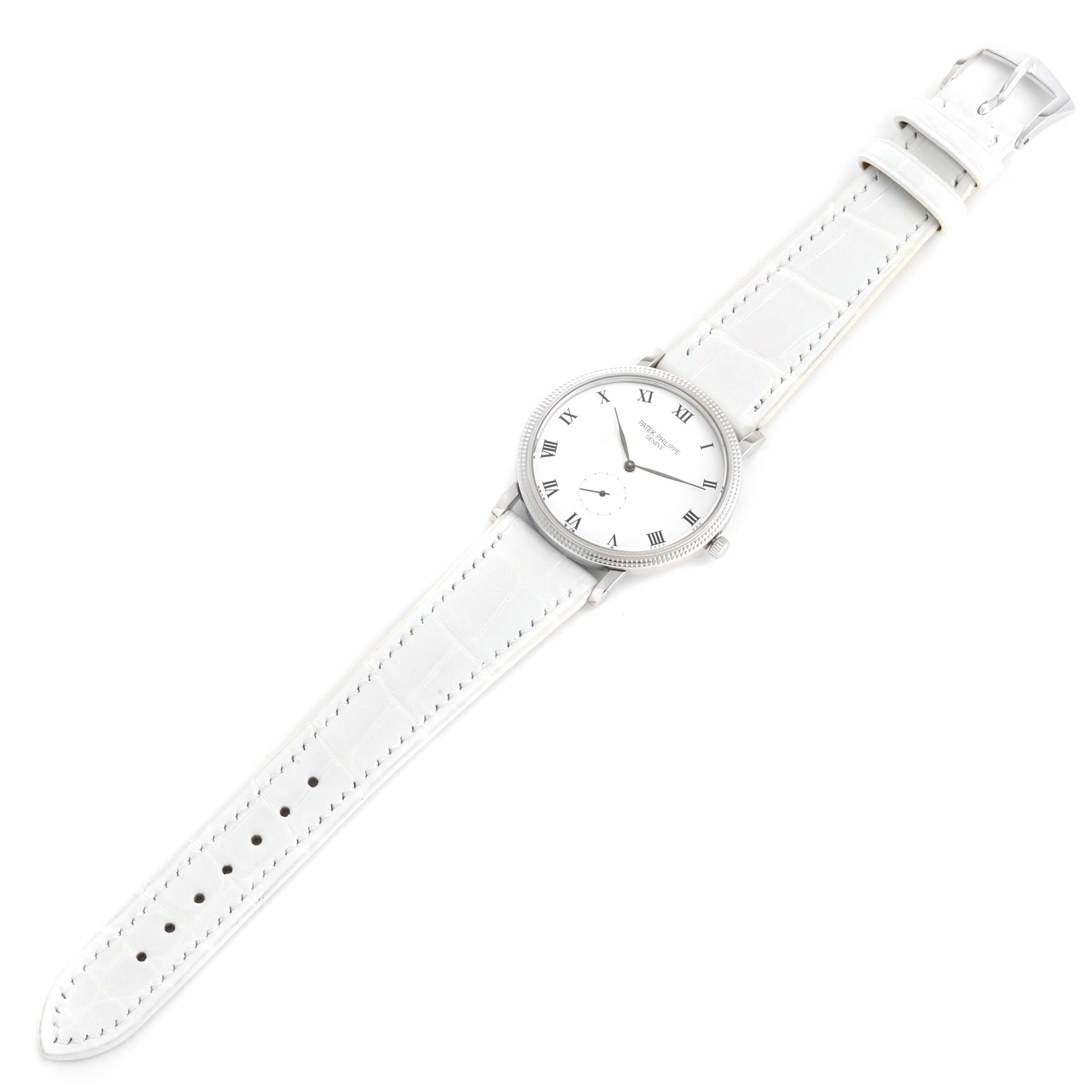 The image shows a top-down view of a Patek Philippe Calatrava 3919G Men's White Gold White Dial 3919G Men's White Gold White Dial watch with a white strap and Roman numeral dial.