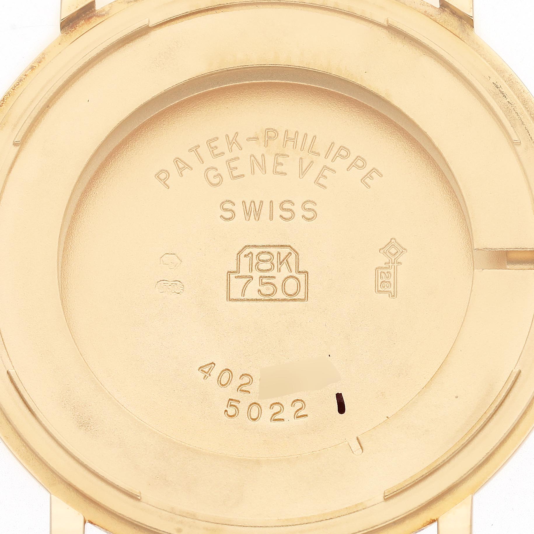 The image shows the back casing of a Patek Philippe Calatrava 5022J-001 Men
s Yellow Gold Champagne Dial 5022J-001 Men
s Yellow Gold Champagne Dial watch, highlighting the brand engravings and gold markings.