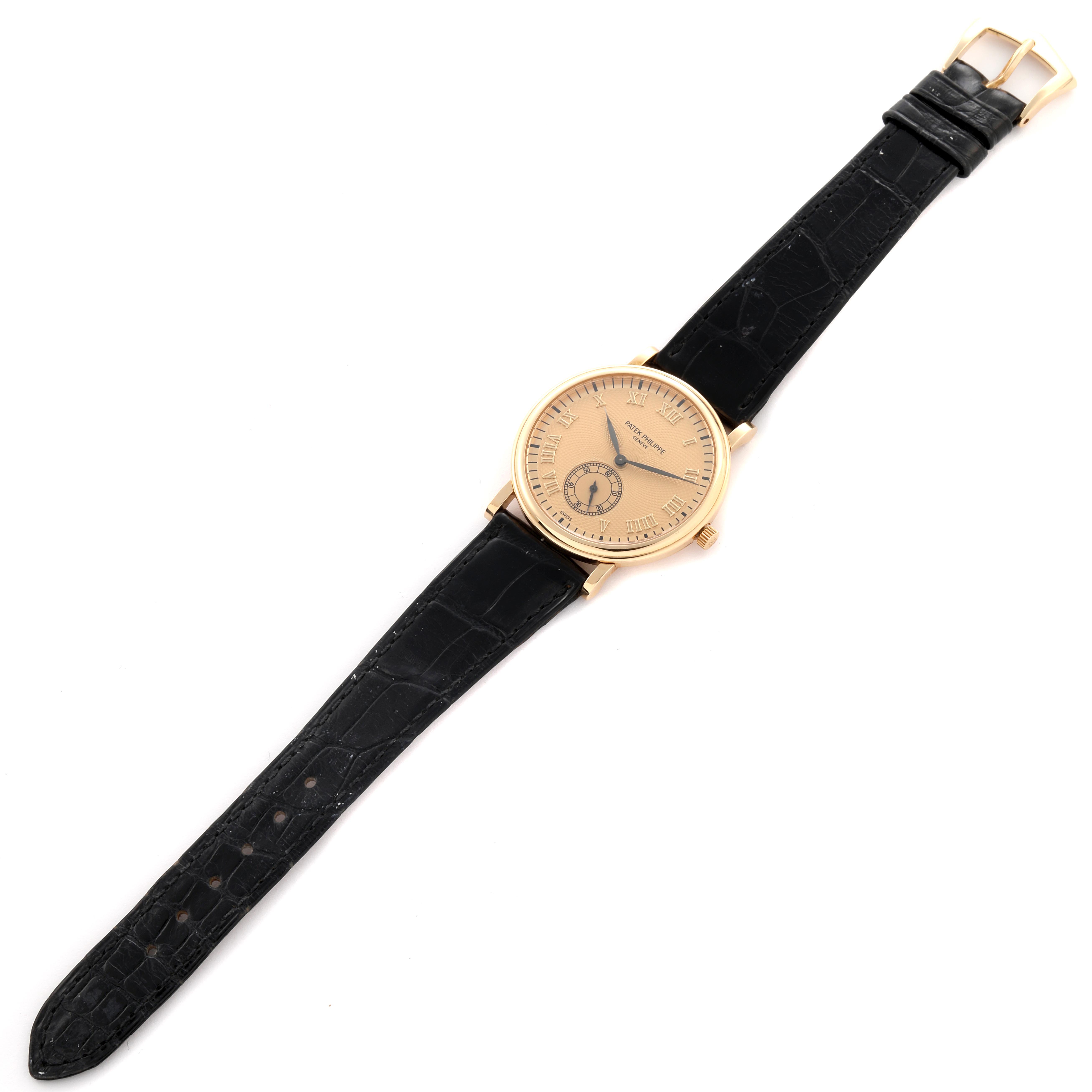 The Patek Philippe Calatrava 5022J-001 Men
s Yellow Gold Champagne Dial 5022J-001 Men
s Yellow Gold Champagne Dial watch is shown from a top-down angle, highlighting the face, hands, case, and black leather strap.