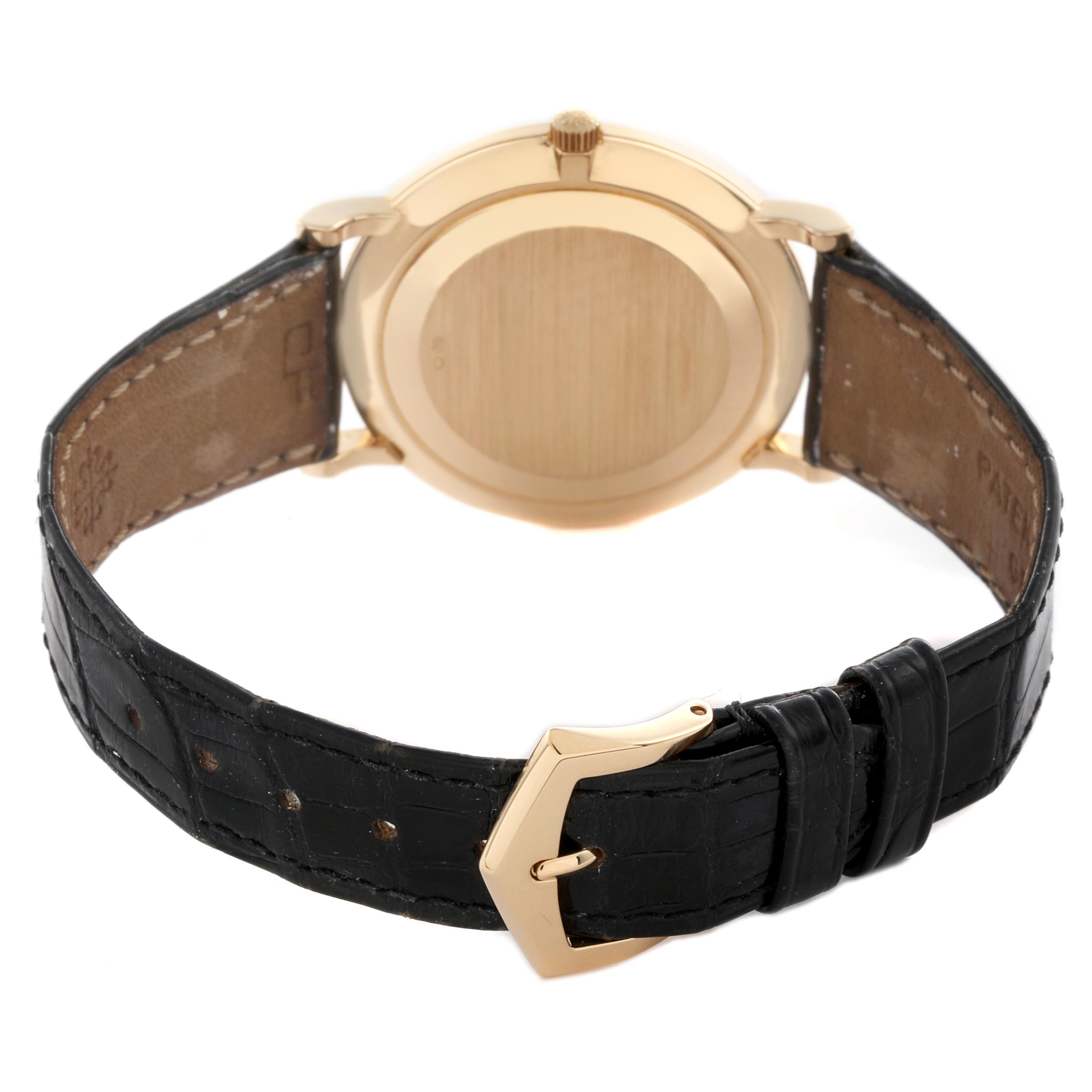 The image shows the back of a Patek Philippe Calatrava 5022J-001 Men
s Yellow Gold Champagne Dial 5022J-001 Men
s Yellow Gold Champagne Dial watch, highlighting the case back, crown, and leather strap with a clasp.