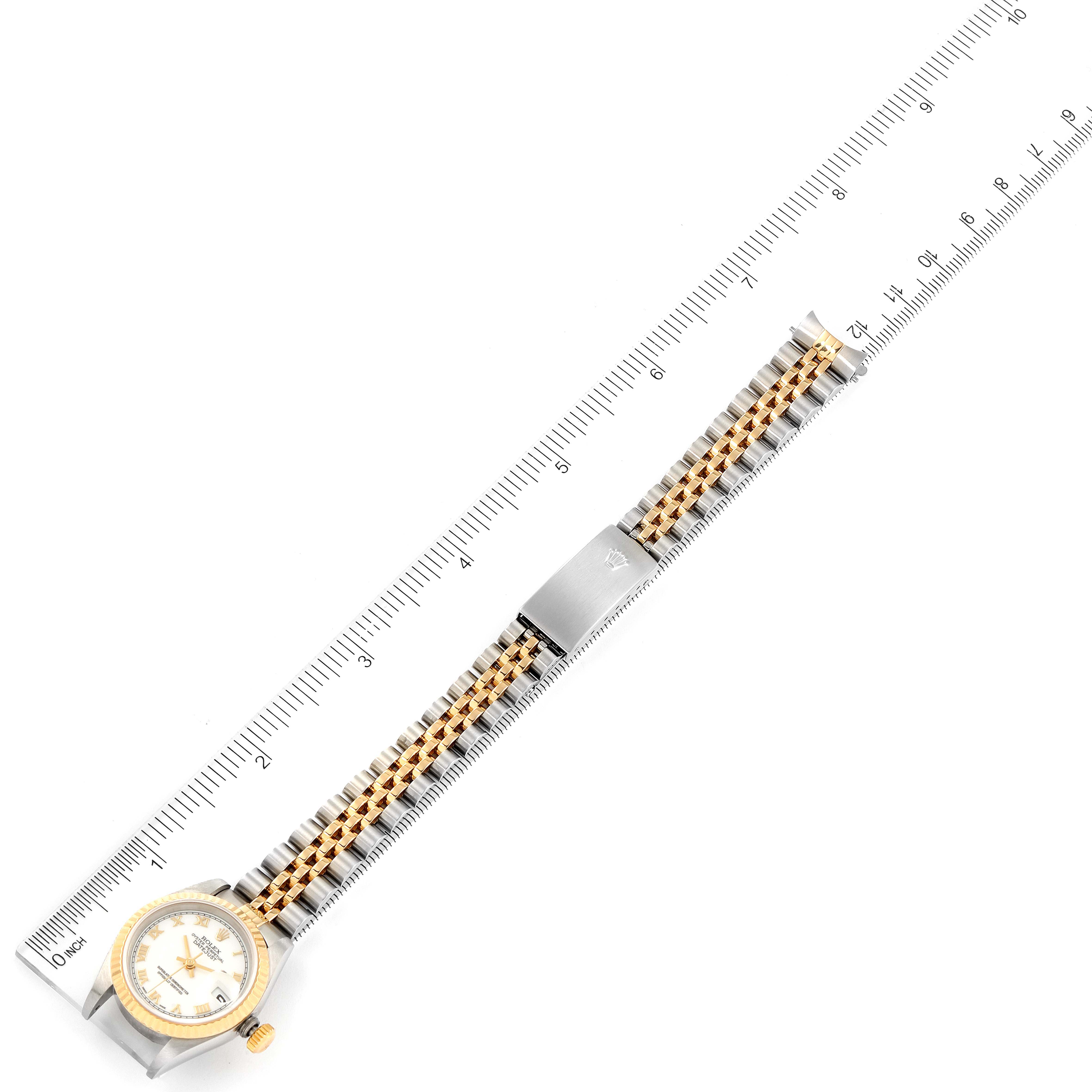 This image shows a Rolex Datejust 79173 Women's Steel and Gold (two tone) White Dial 79173 Women's Steel and Gold (two tone) White Dial watch laid flatly on a ruler, displaying both the face and bracelet.