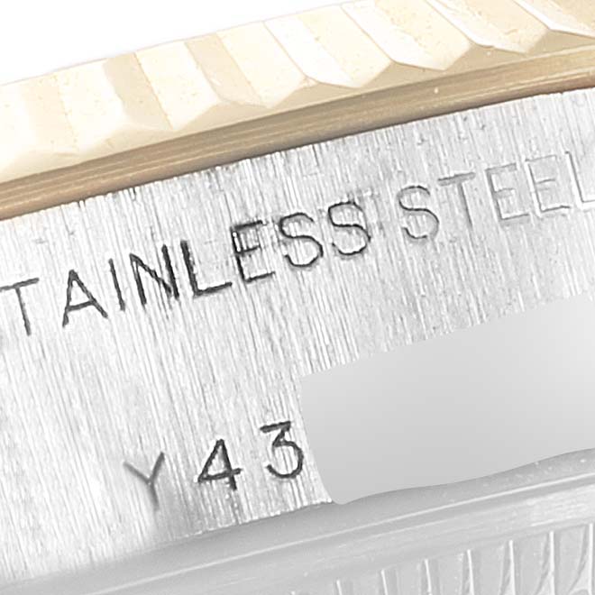 This close-up image of a Rolex Datejust 79173 Women's Steel and Gold (two tone) White Dial 79173 Women's Steel and Gold (two tone) White Dial watch shows the engraved stainless steel material and a part of the fluted bezel.