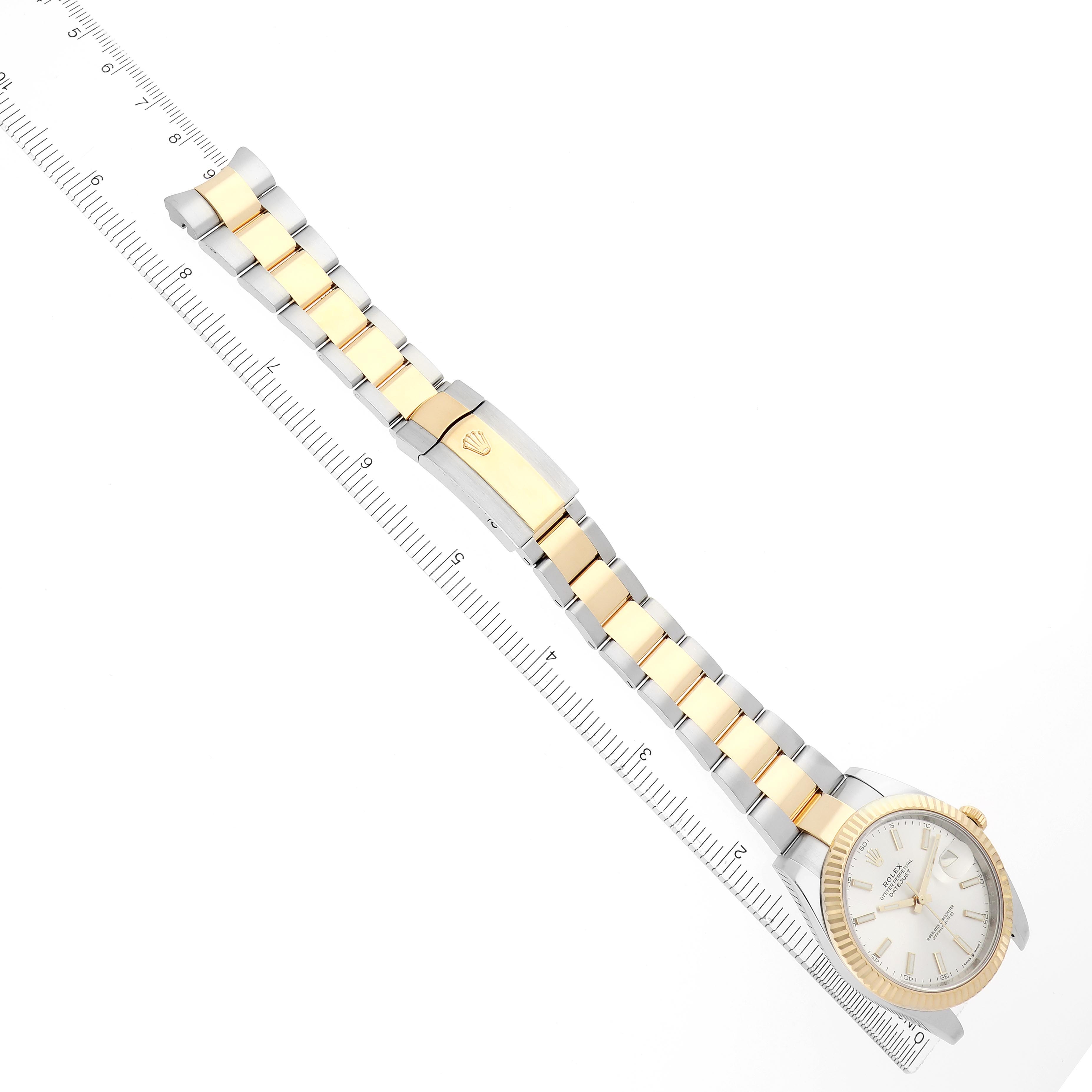 The Rolex Datejust 41 126333 Men
s Steel and Gold (two tone) Silver Dial 126333 Men
s Steel and Gold (two tone) Silver Dial is shown at an angled view, highlighting its case, bezel, and two-tone bracelet next to a ruler.