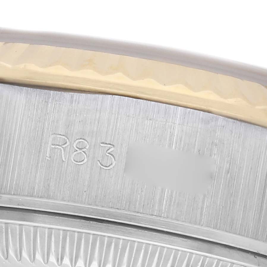 The image shows a close-up of the Rolex Datejust 69173 Women
s Steel and Gold (two tone) Champagne Dial 69173 Women
s Steel and Gold (two tone) Champagne Dial
s fluted bezel and engraved serial number on the case side.