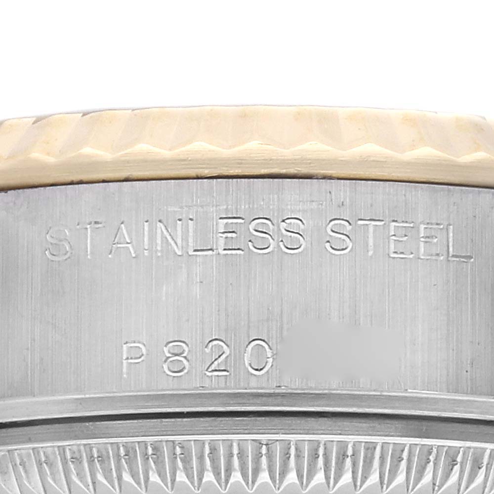 The image shows a close-up of the side of a Rolex Datejust 79173 Women
s Steel and Gold (two tone) Champagne Dial 79173 Women
s Steel and Gold (two tone) Champagne Dial watch, highlighting the engravings and fluted bezel.