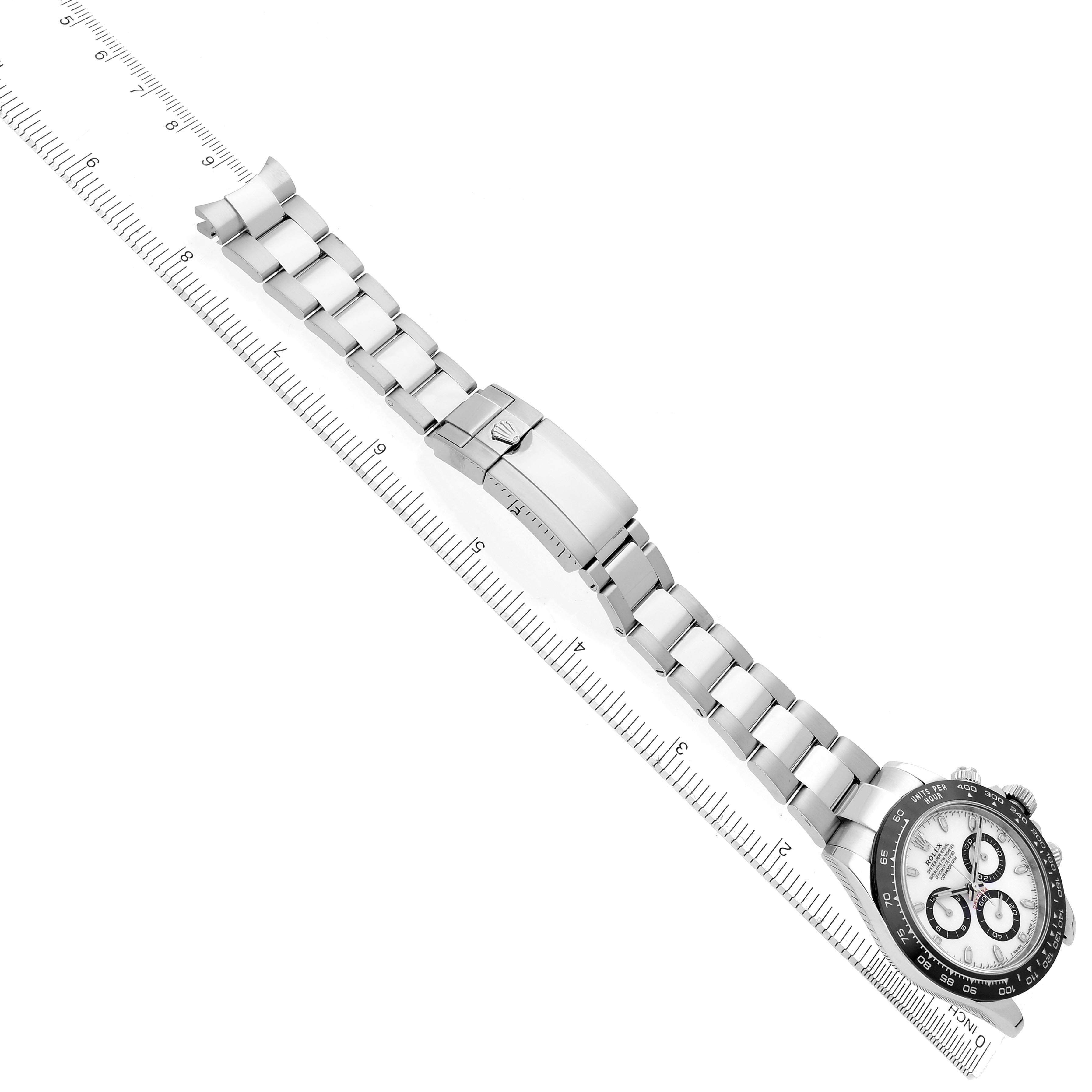 The Rolex Daytona 116500LN Men's Stainless Steel White Dial 116500LN Men's Stainless Steel White Dial watch is shown at an angle highlighting the full bracelet and clasp against a ruler for scale.