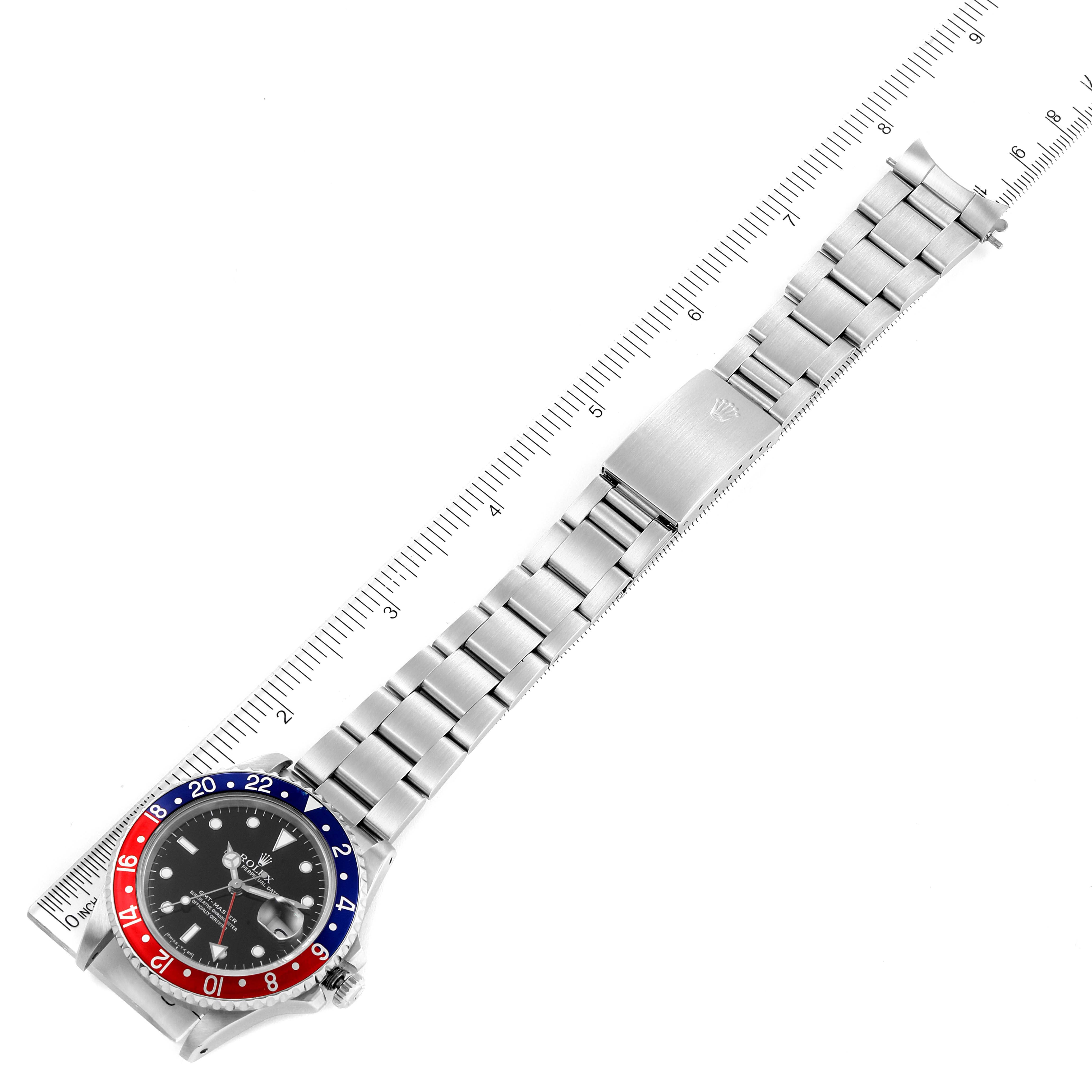 The image shows a top-down view of a Rolex GMT-Master 16700 Men's Stainless Steel Black Dial 16700 Men's Stainless Steel Black Dial watch with its bracelet fully extended and a ruler beside it for scale.