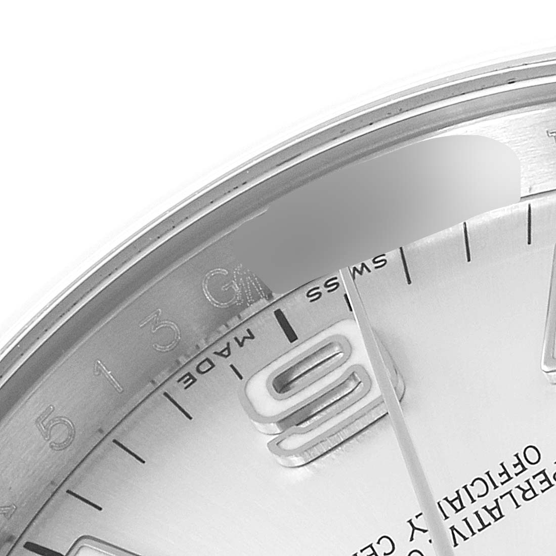 This close-up of the Rolex Oyster Perpetual 116000 Men's Stainless Steel Silver Dial 116000 Men's Stainless Steel Silver Dial watch shows part of the dial, bezel, and the "6" hour marker.