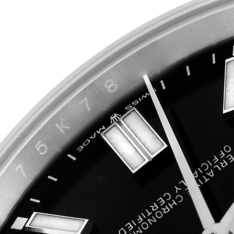 The image shows a close-up of the Rolex Oyster Perpetual 124300 Men
s Stainless Steel Black Dial 124300 Men
s Stainless Steel Black Dial
s dial, highlighting indices, part of the hand, and "SWISS MADE."