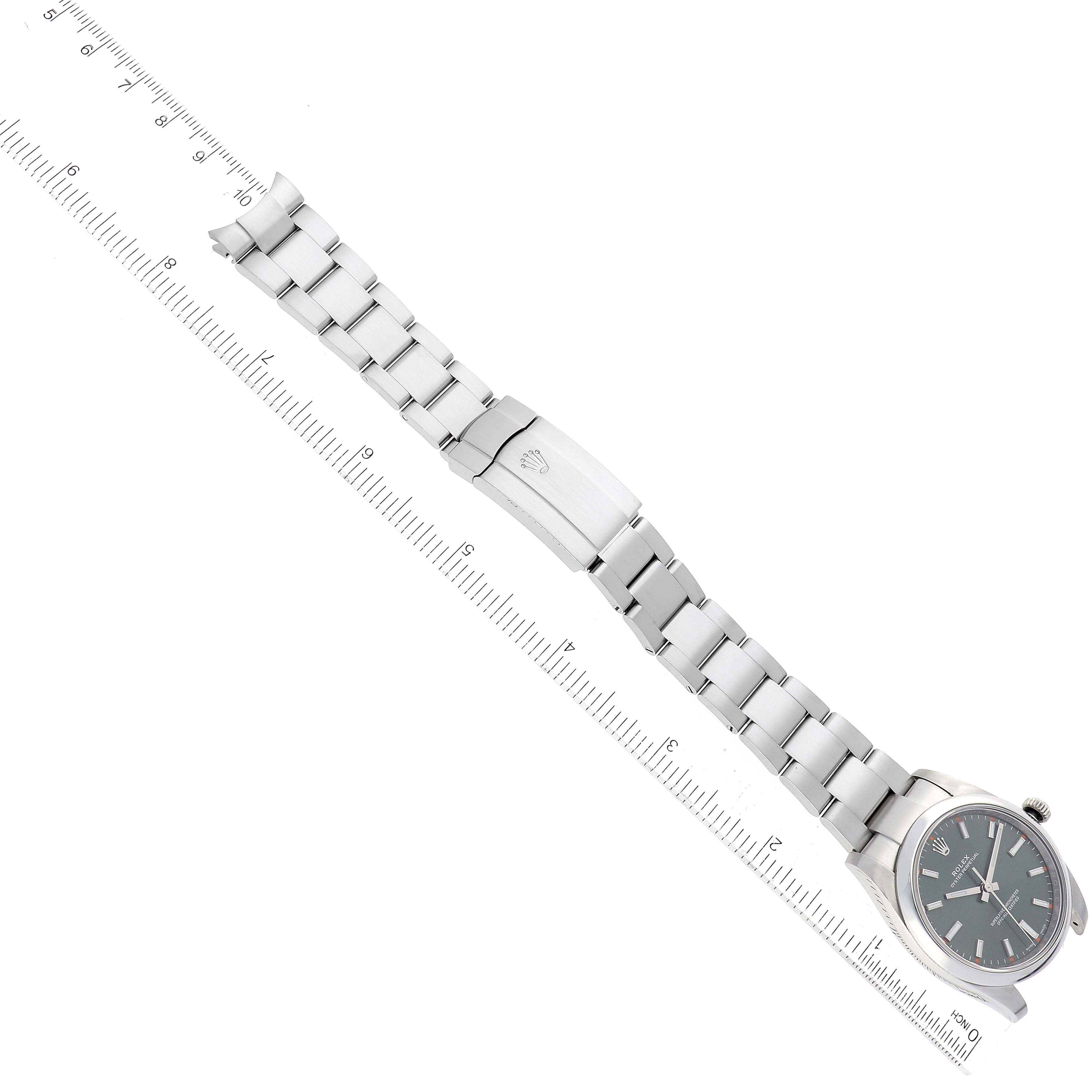 The image shows a top-down view of a Rolex Oyster Perpetual 114200 Men's Stainless Steel Green Dial 114200 Men's Stainless Steel Green Dial watch with the bracelet fully extended along a ruler.