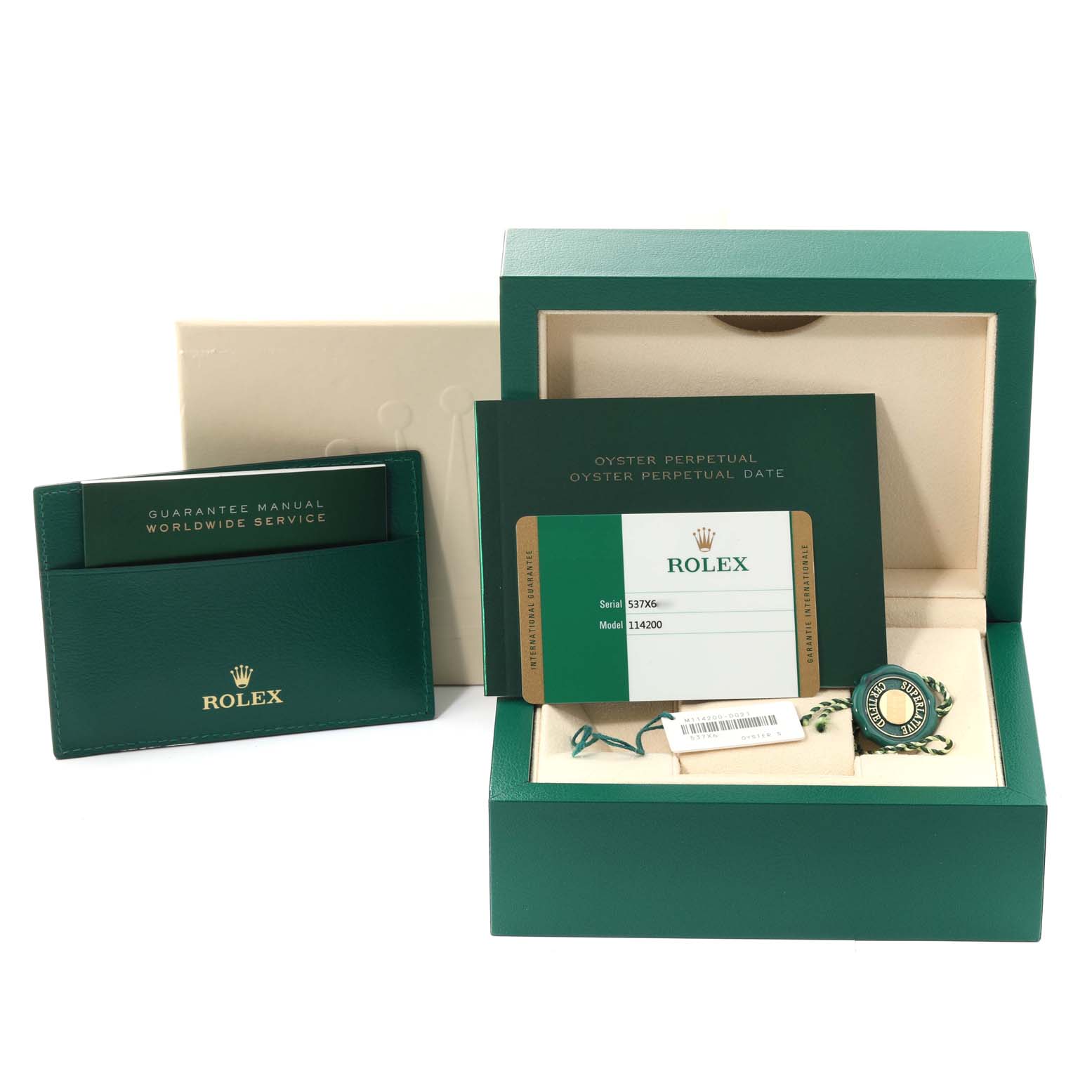 This image shows the packaging, guarantee manual, warranty card, and tags for the Rolex Oyster Perpetual 114200 Men's Stainless Steel Green Dial 114200 Men's Stainless Steel Green Dial watch, model 114200.