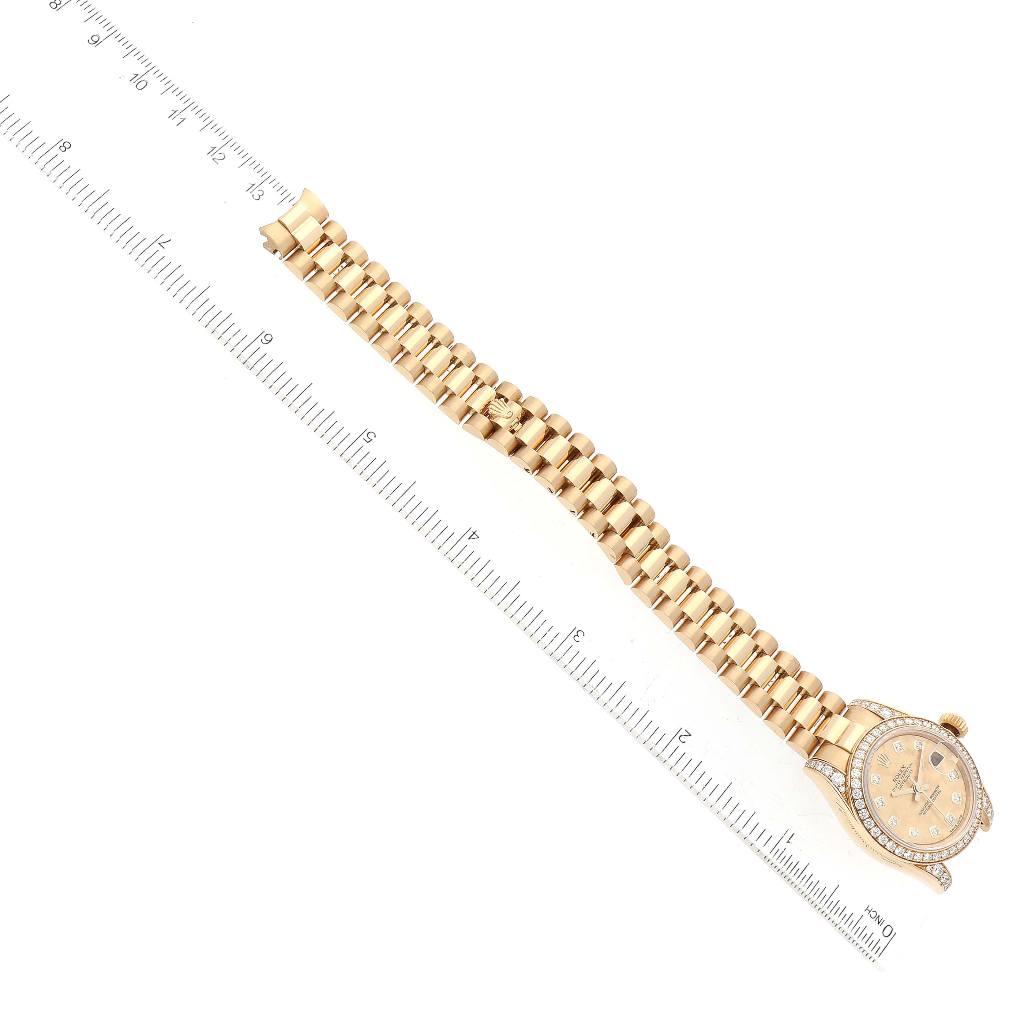 The Rolex President 179158 Women
s Yellow Gold Champagne Dial 179158 Women
s Yellow Gold Champagne Dial watch is shown flat with its bracelet extended next to a ruler for scale.