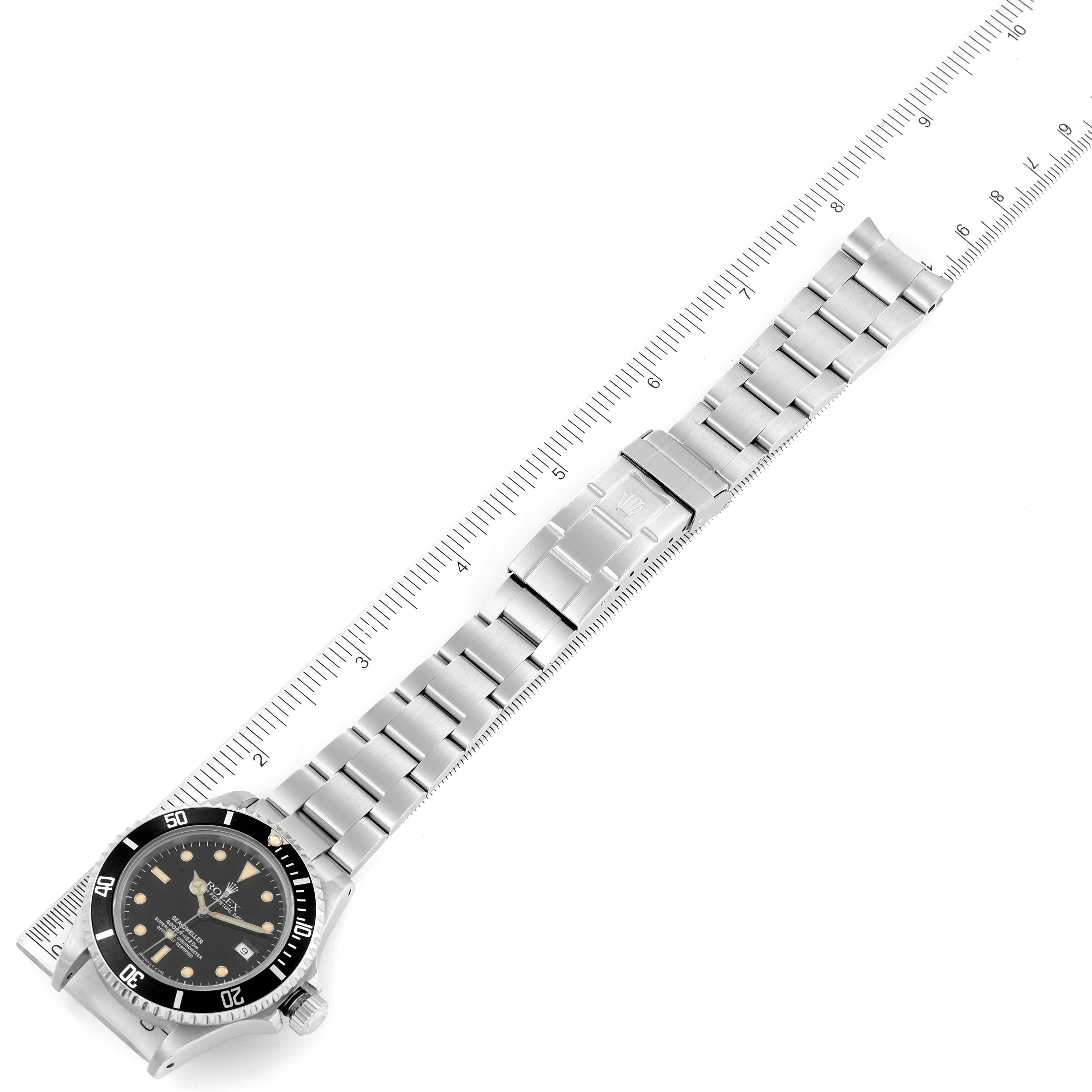 The image shows a top-down view of the Rolex Sea-Dweller 16600 Men
s Stainless Steel Black Dial 16600 Men
s Stainless Steel Black Dial watch, focusing on the dial, bezel, bracelet, and clasp, with a ruler for scale.