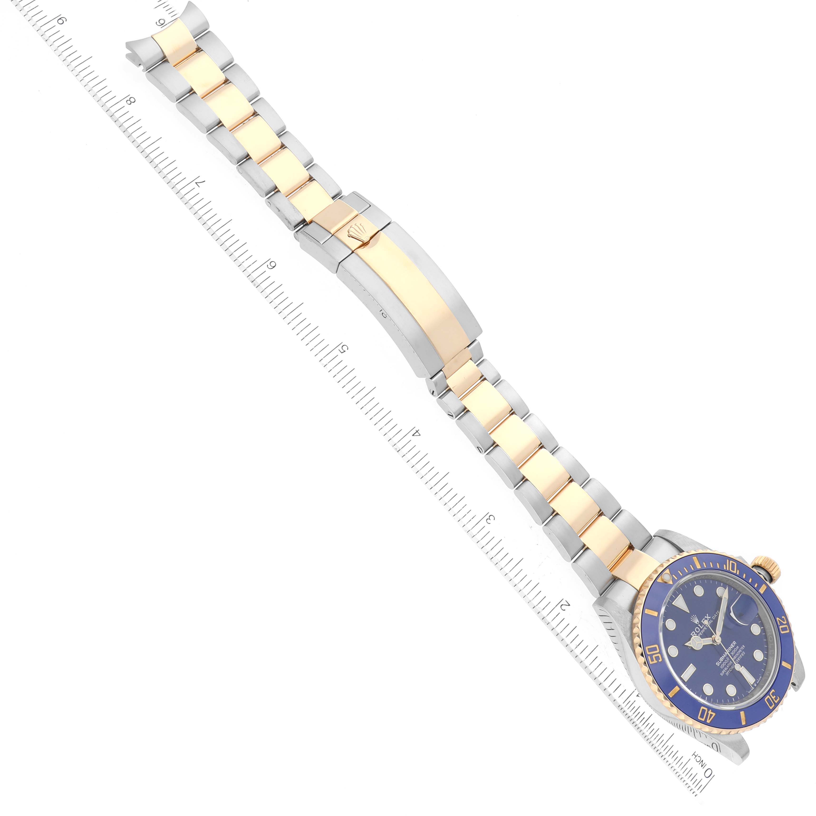 The image shows a Rolex Submariner 126613LB Men's Steel and Gold (two tone) Blue Dial 126613LB Men's Steel and Gold (two tone) Blue Dial watch, angled diagonally, displaying the full bracelet and the face with a ruler for scale.