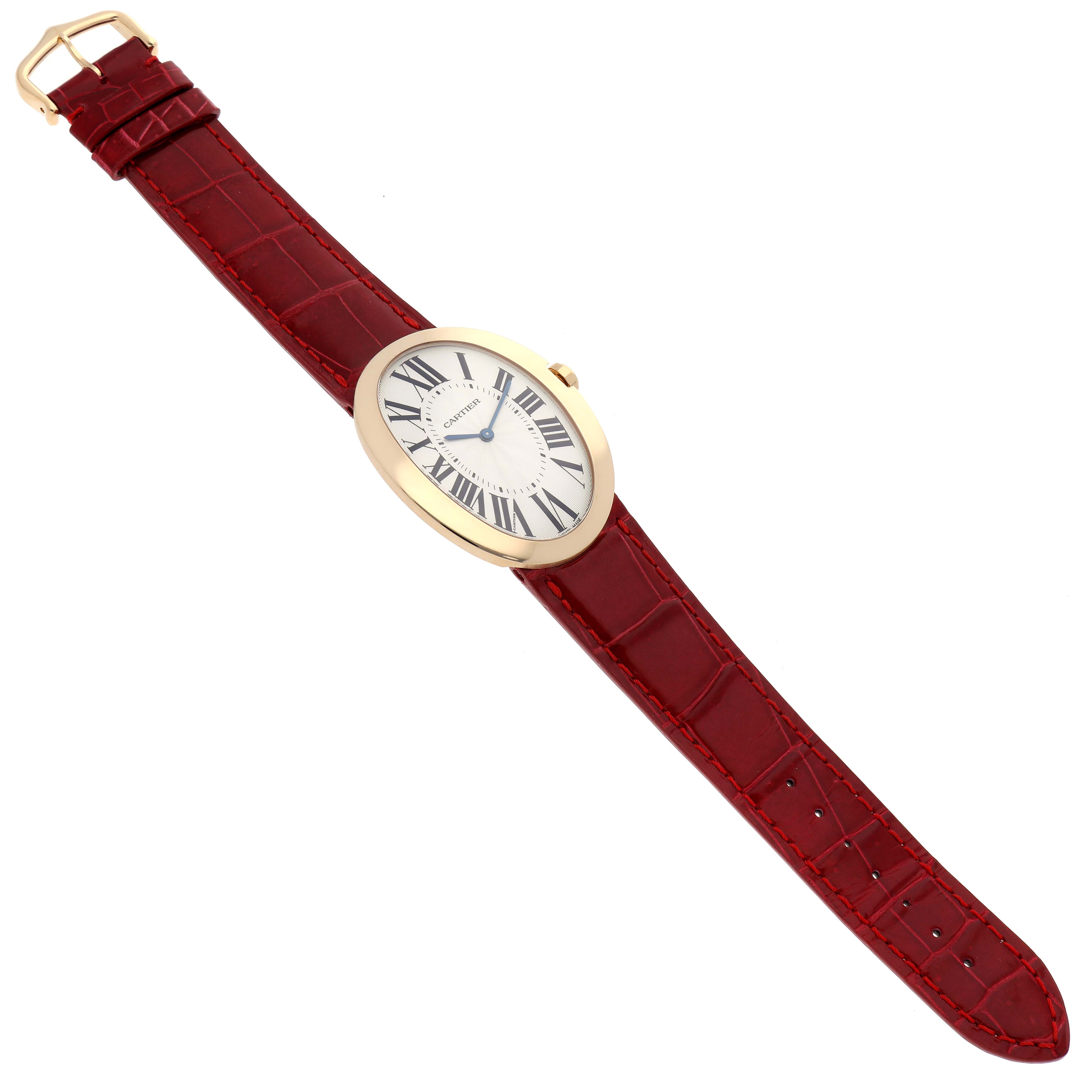 The Cartier Baignoire W8000013 Women's Yellow Gold Silver Dial W8000013 Women's Yellow Gold Silver Dial watch is shown from a top-down angle, displaying its oval face, Roman numerals, and red leather strap.
